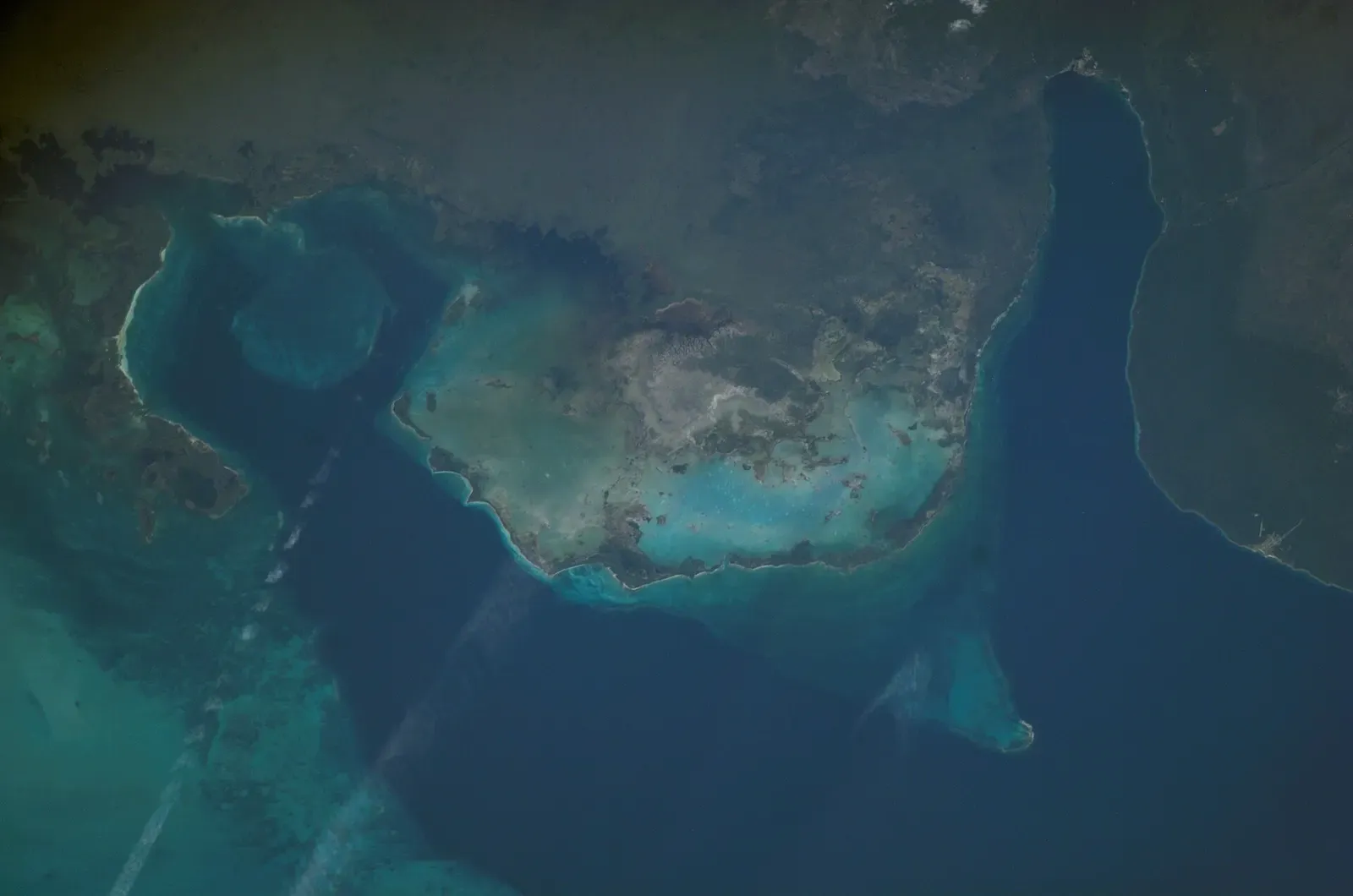 Astronaut photograph of the Guanahacabibes peninsula, its shallow turquoise reef platform and the deep bay of Bahia de Corrientes — María la Gorda