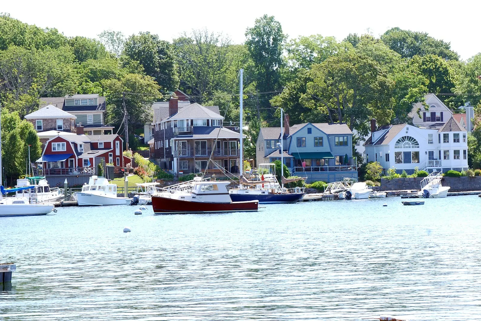 Wooden houses among trees above Smith Cove, with lobster boats and sailboats on moorings — Cape Ann & Stellwagen Bank