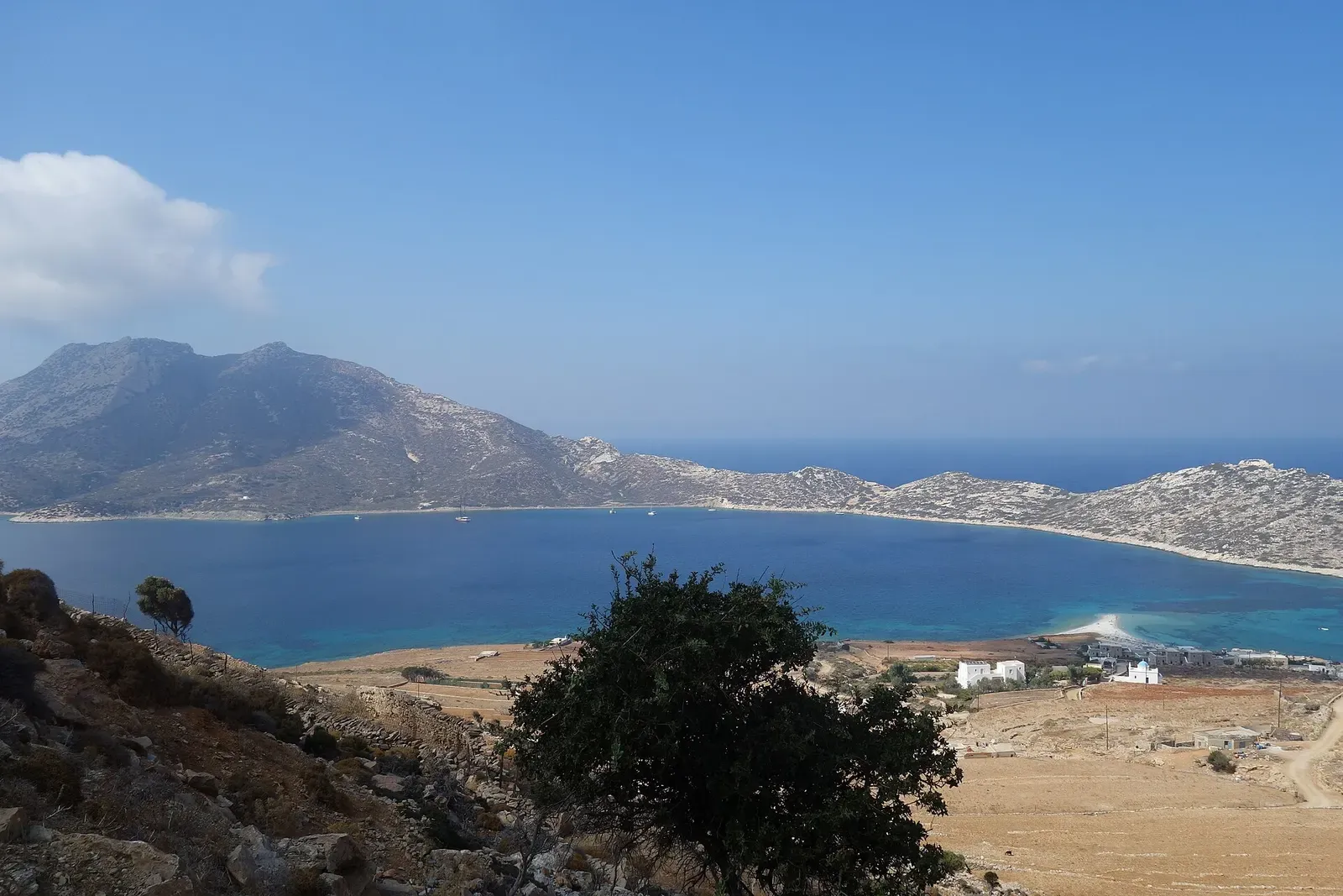 Coastal view of the Agios Prokopios settlement and beach on Amorgos, with Nikouria island offshore.