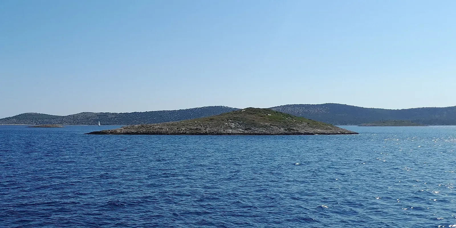 Babuljaš Veli, a low green-topped islet rising from open water northeast of Žut — Babuljasi, Kornati Islands.