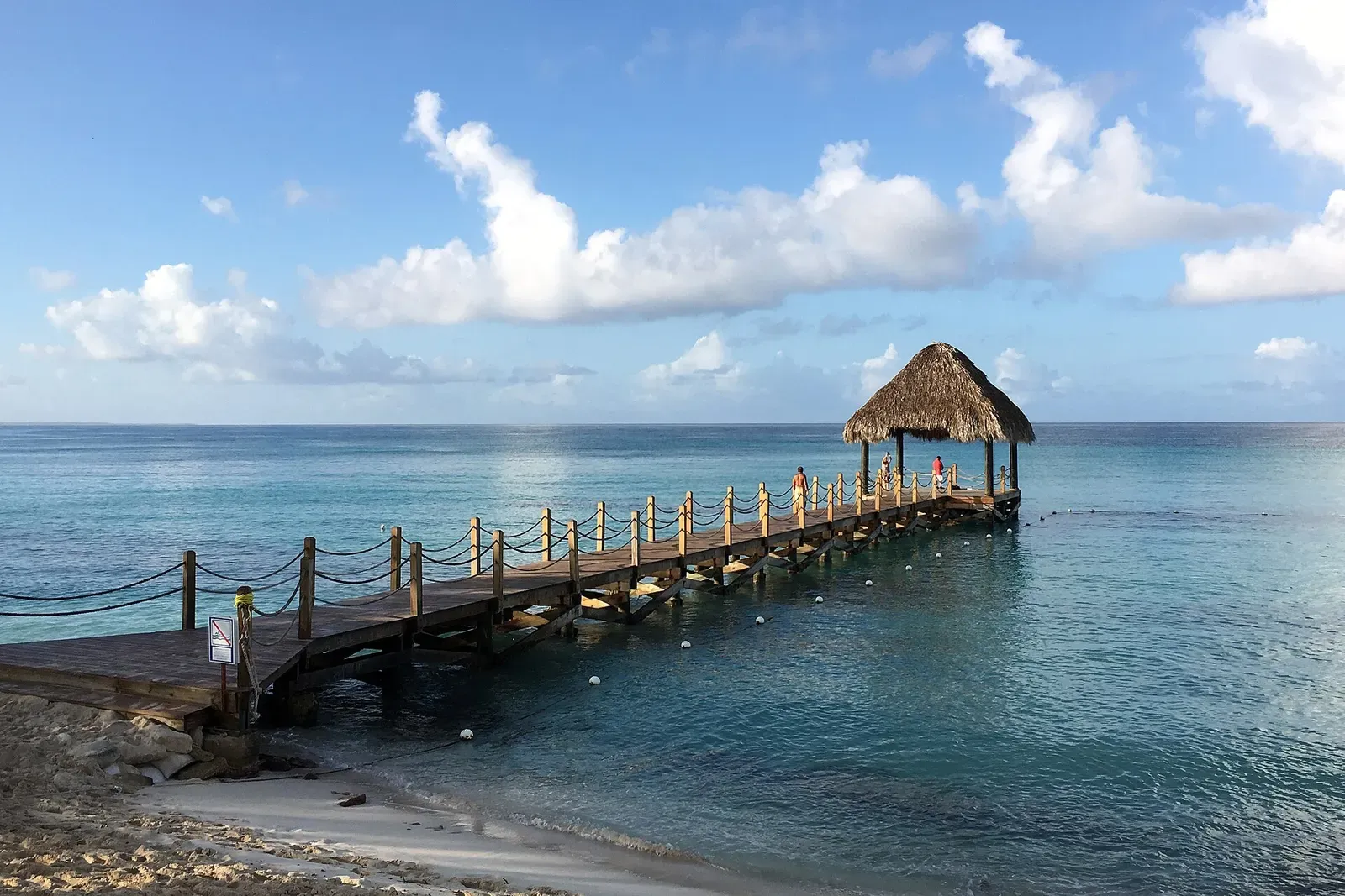 Thatched wooden pier running out over shallow turquoise water at Dominicus beach