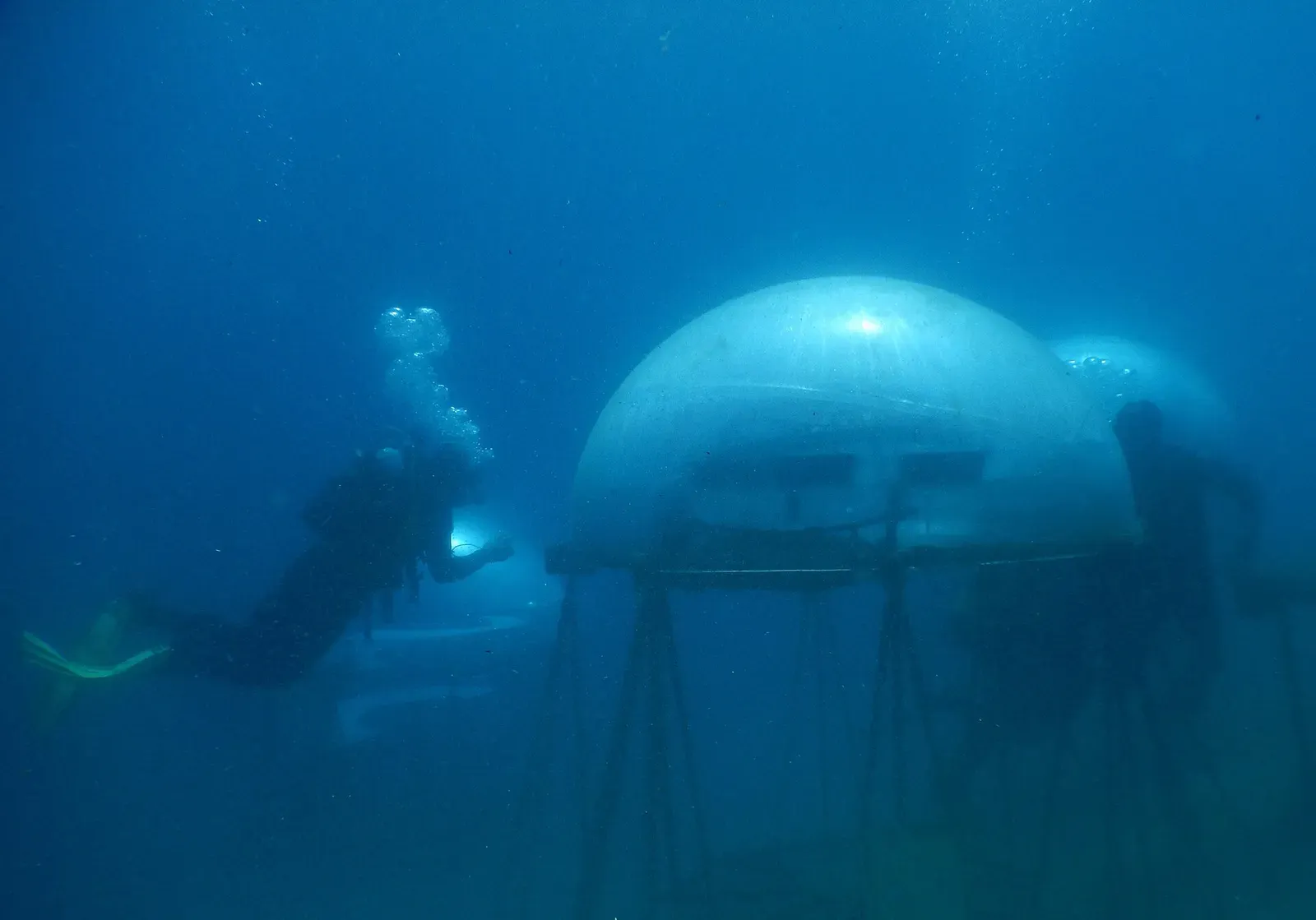 A diver approaching a domed biosphere structure on the seabed