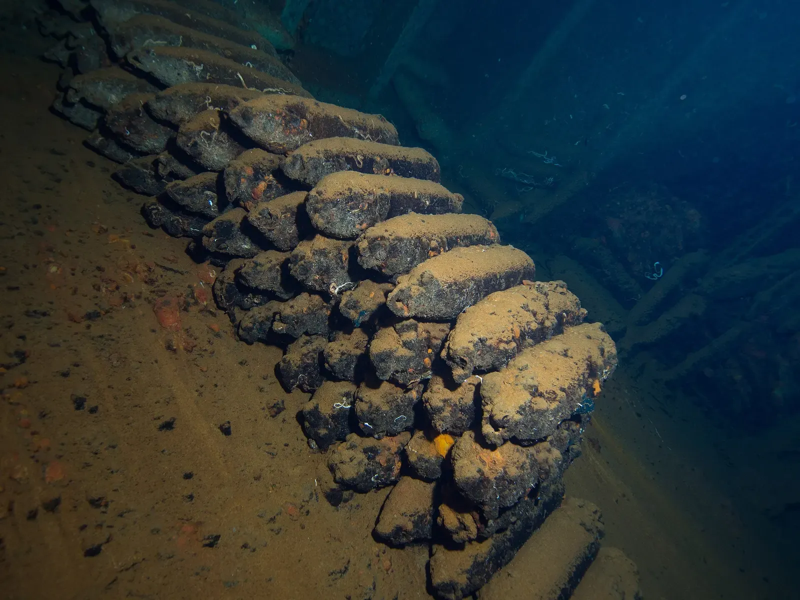 Stacked rows of silt-covered aerial bombs inside a dark shipwreck hold — Sudanese Red Sea