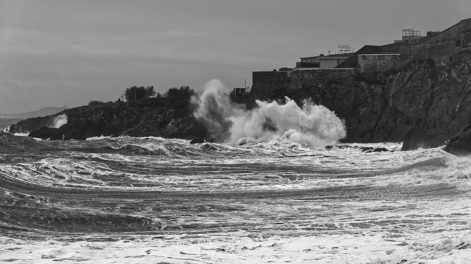 Black and white image of waves breaking against the fortified wall of the Théâtre de la Mer in Sète