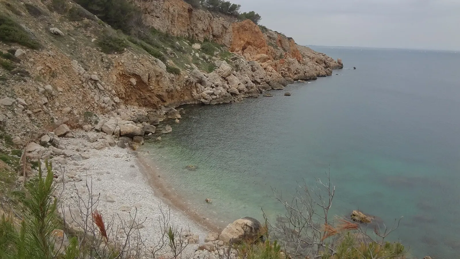 Orange cliffs and clear water of the cove beside Illa Mateua