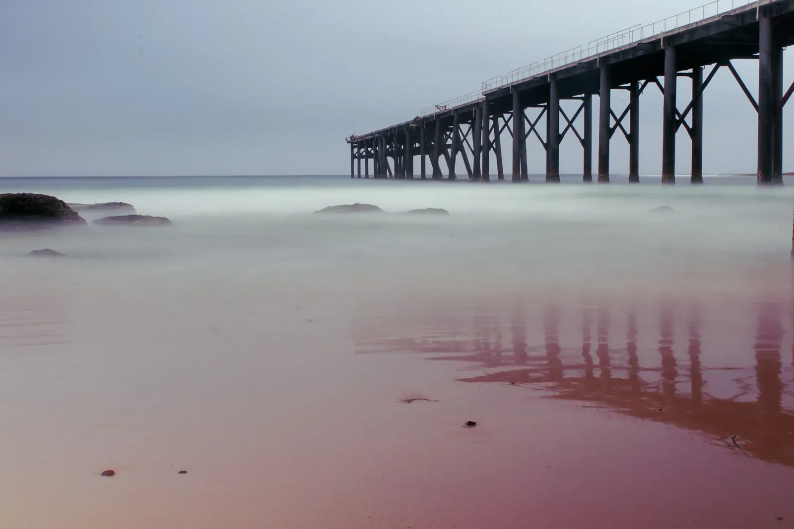 Long exposure of the coal loading jetty's pylons receding into misty water at Catherine Hill Bay