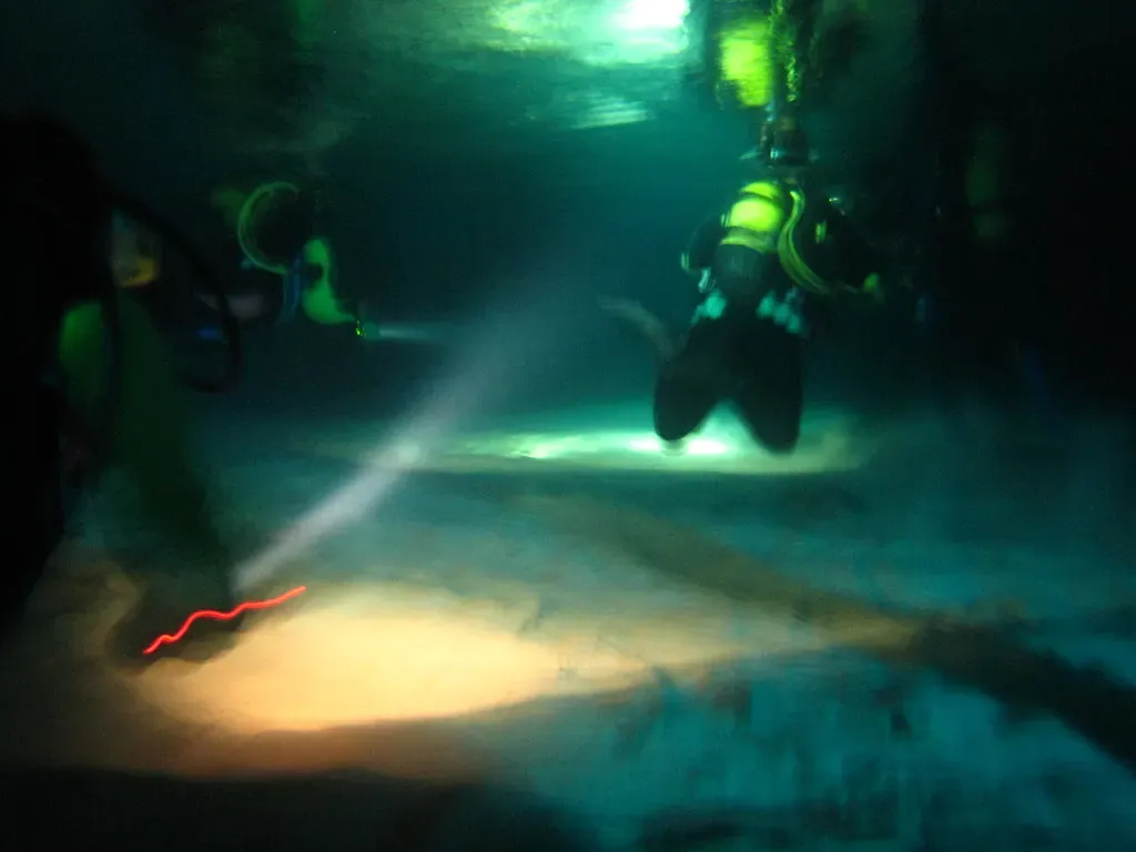 Divers with torchlight exploring the tunnel inside Elephant Cave — Crete