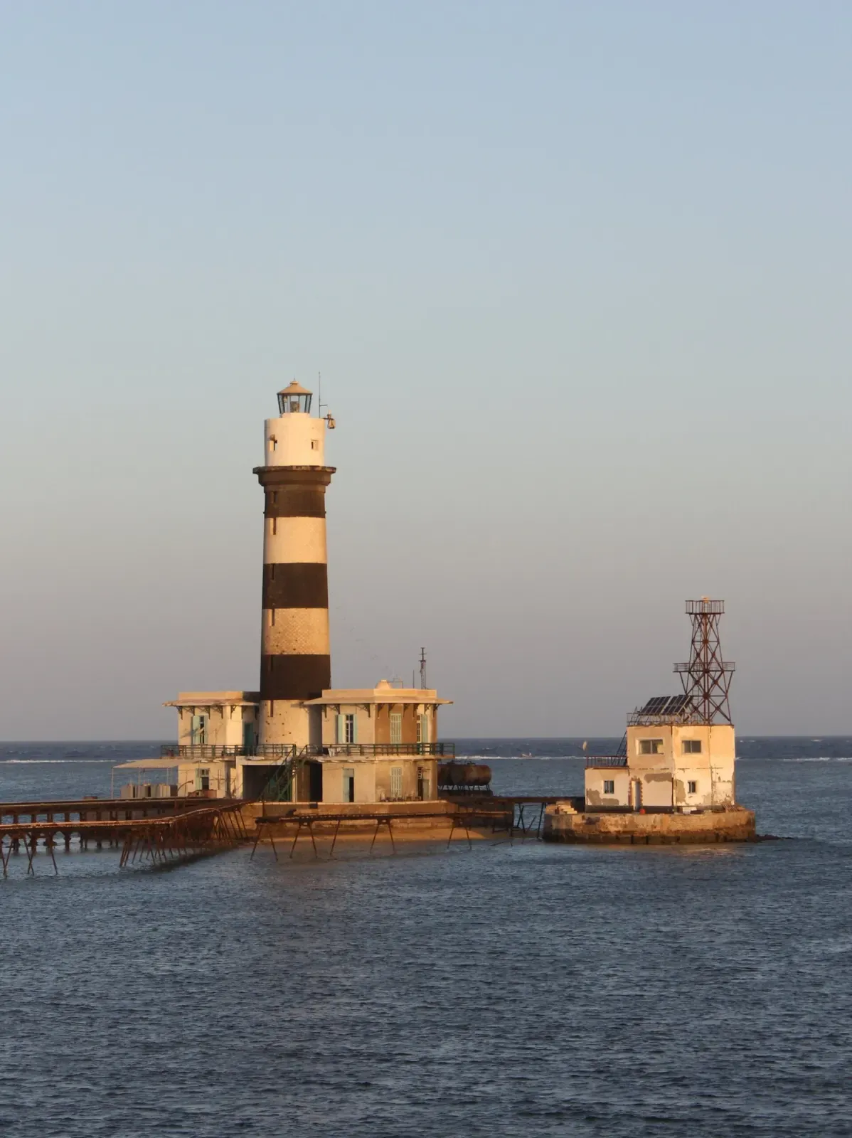 A black-and-white striped lighthouse standing on stilts above the open sea — Daedalus Reef, Brothers & Daedalus