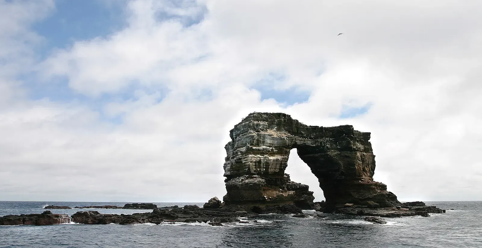 The intact rock arch rising from the sea off Darwin Island, before it collapsed — Darwin's Arch.