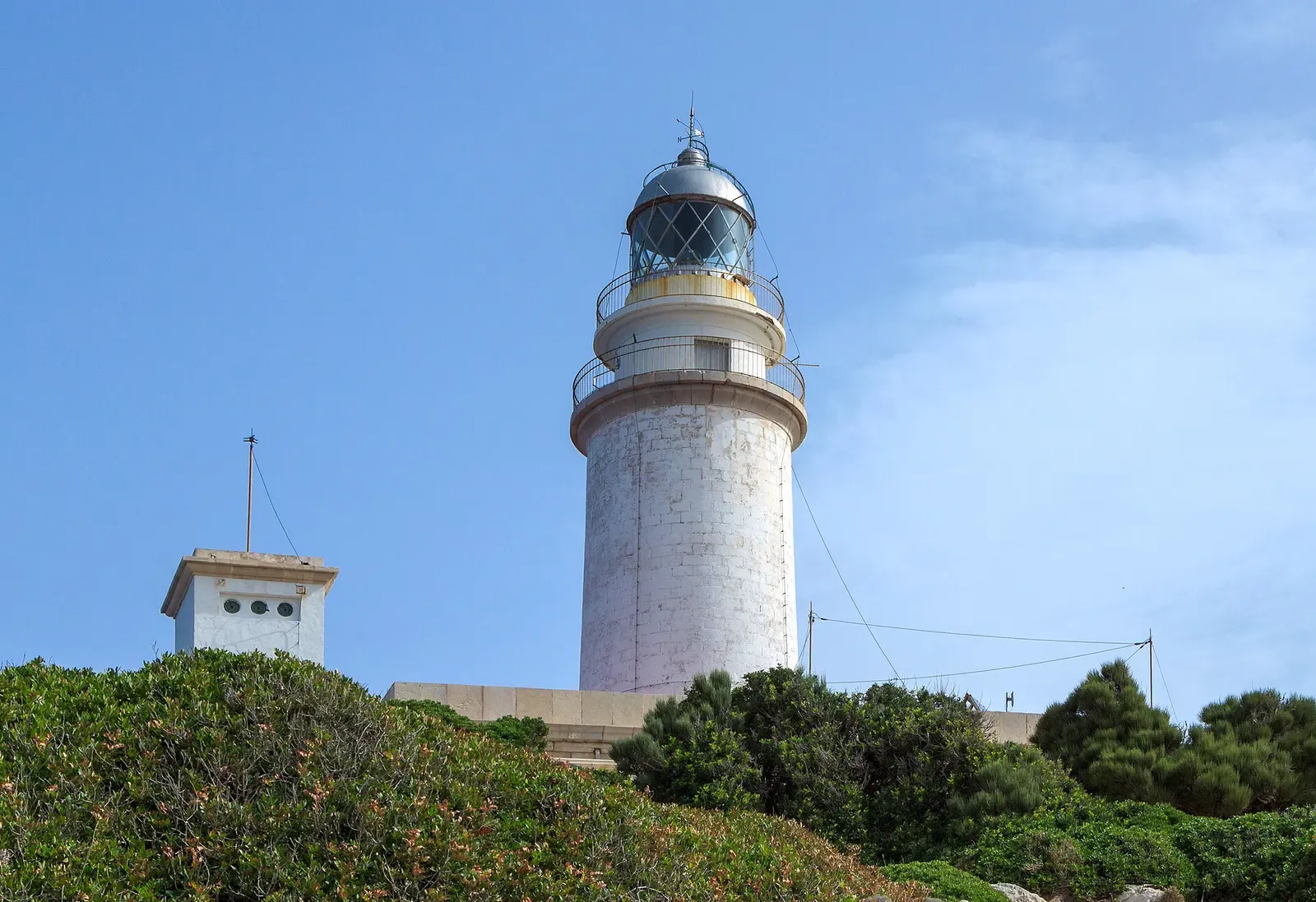 Formentor lighthouse with its glass lantern room framed by cliffside scrub