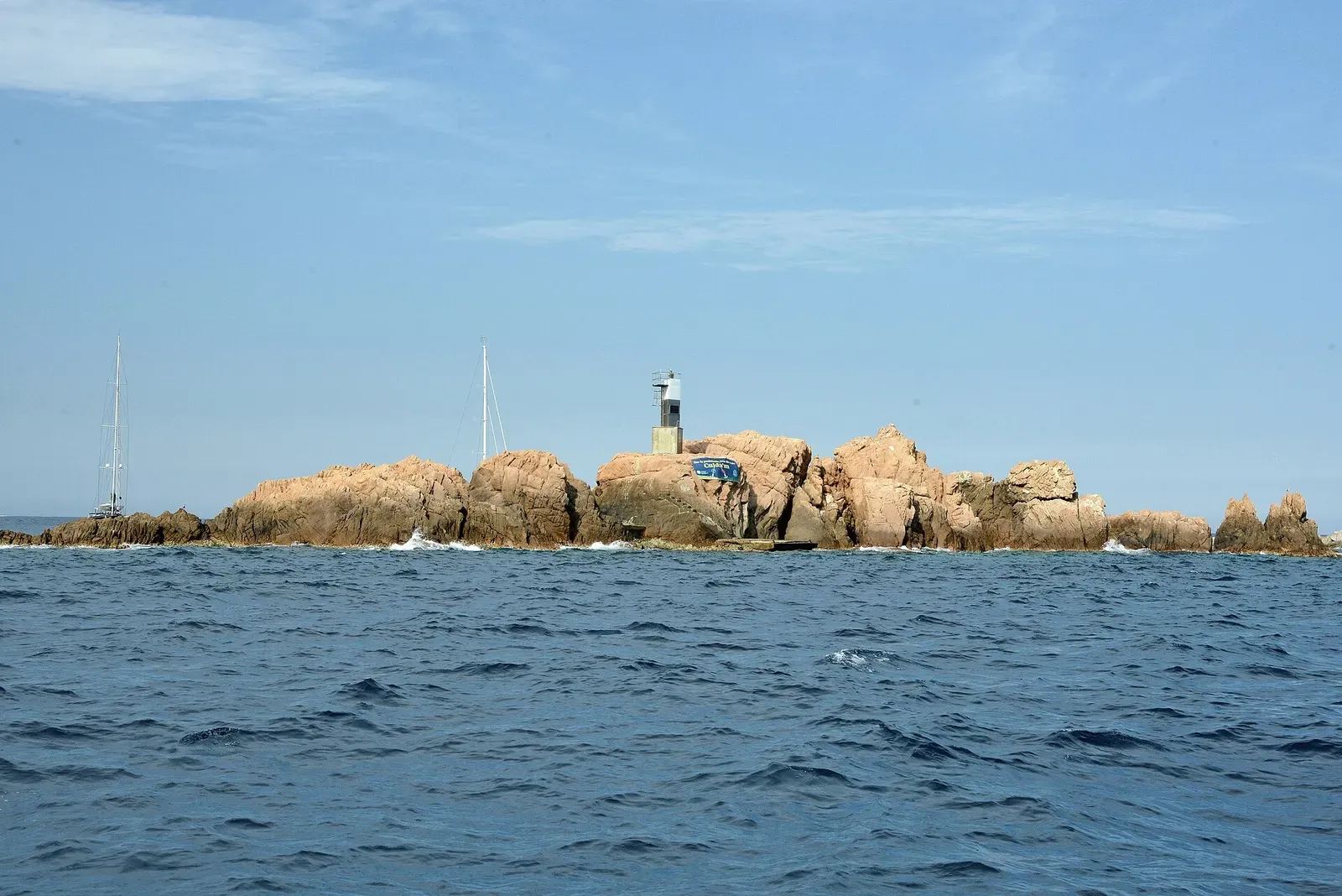 Lighthouse on the rocky Illes Formigues islets with a boat moored alongside