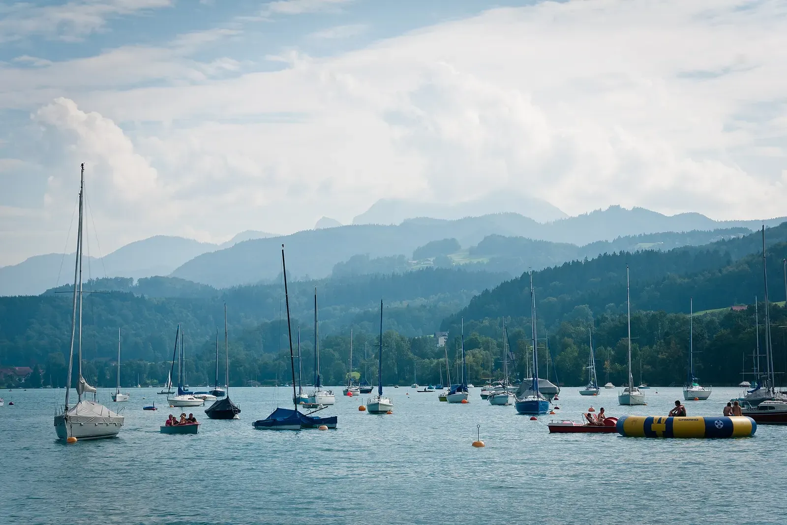 Yachts on the calm surface of Attersee with hazy mountains beyond
