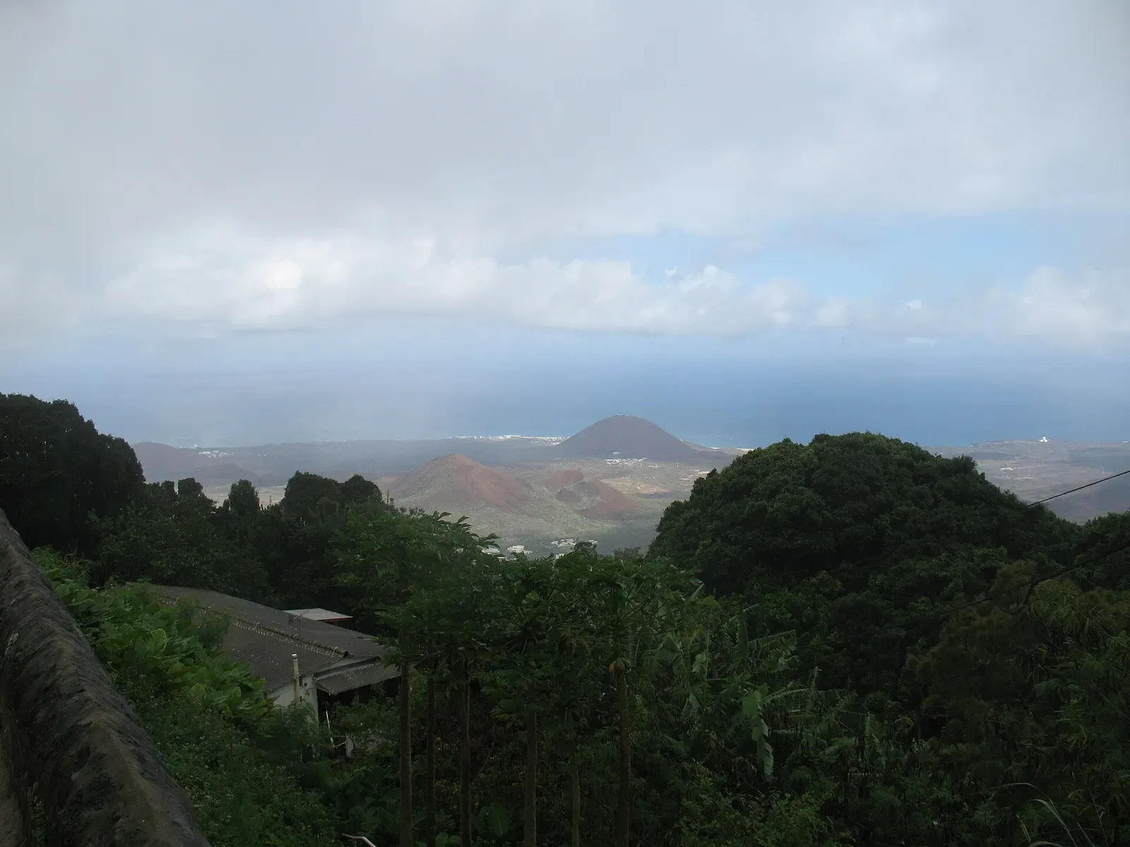 Red volcanic cinder cones and scrubland sloping down to the sea, with Georgetown small in the distance — Ascension Island