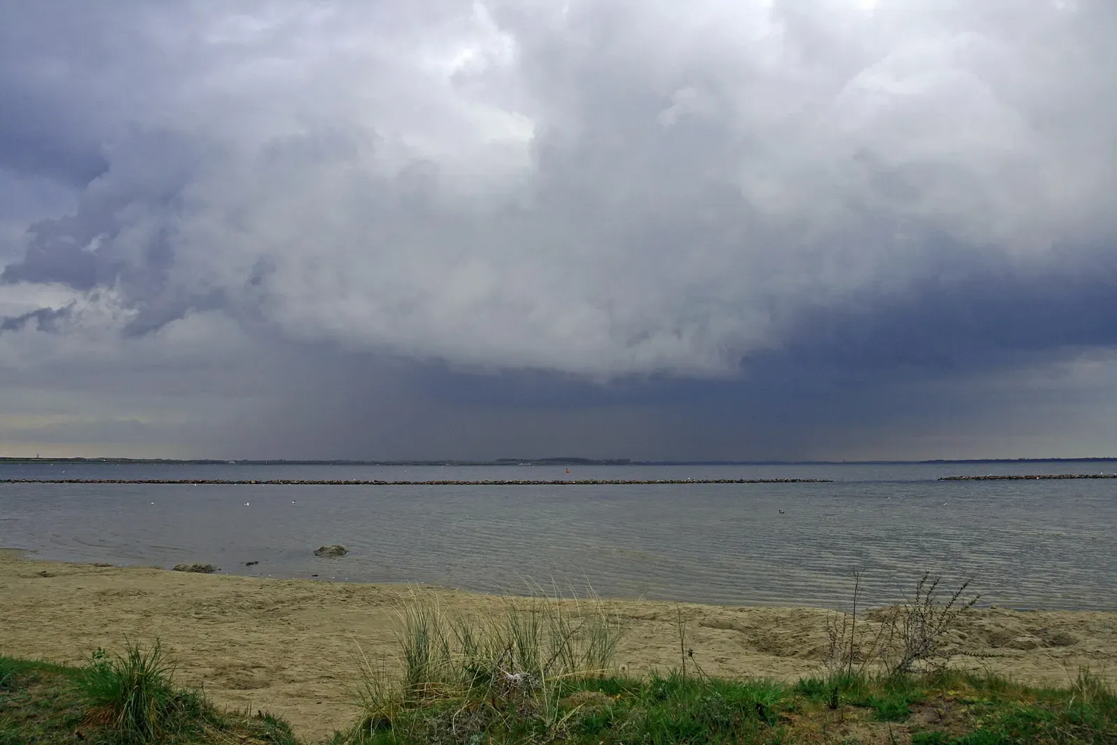 Dark storm clouds gathering over the flat surface of the Grevelingenmeer — Den Osse