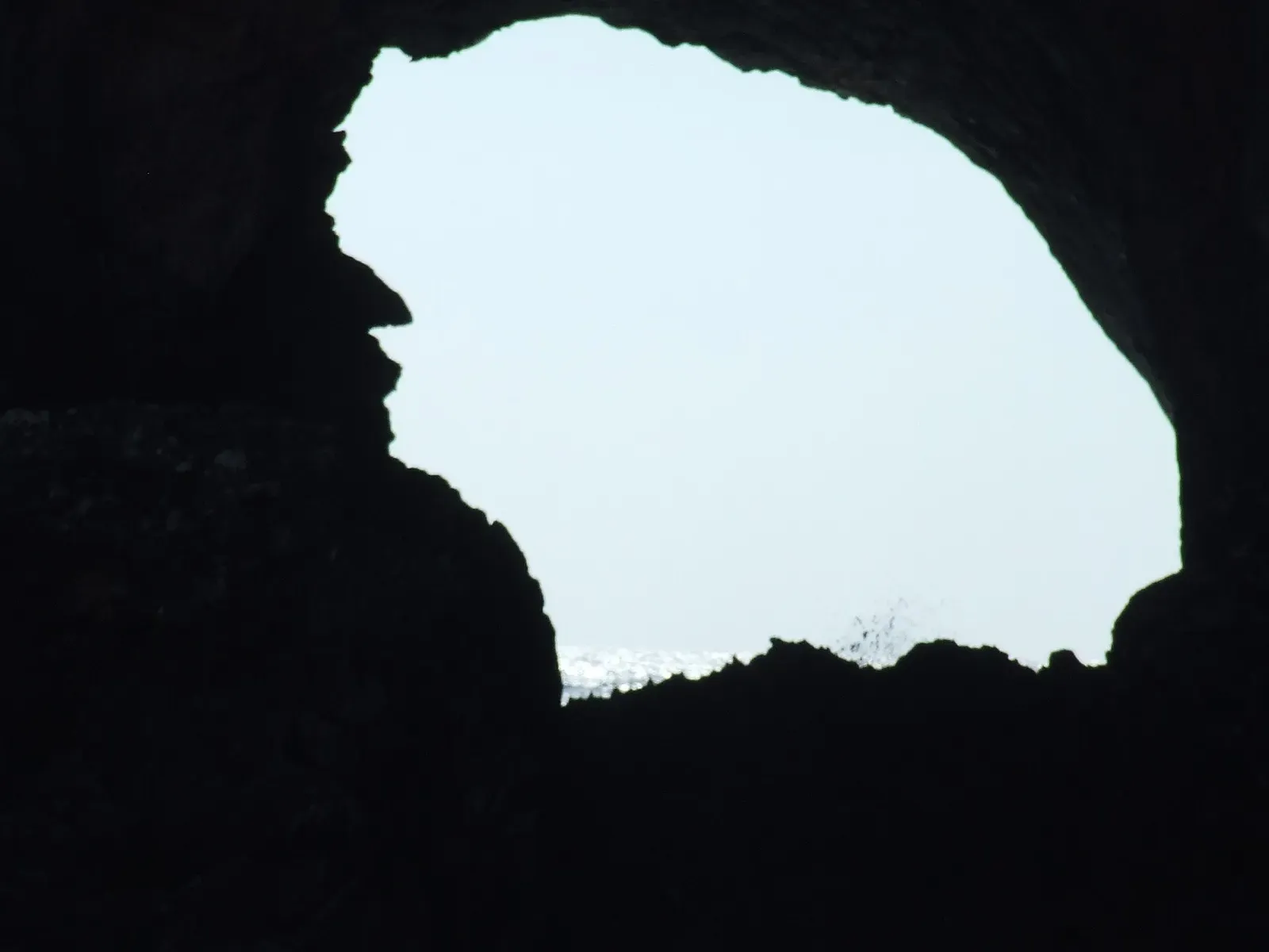 Sunlight through the natural rock arch that tunnels through Isola Foradada — Capo Caccia