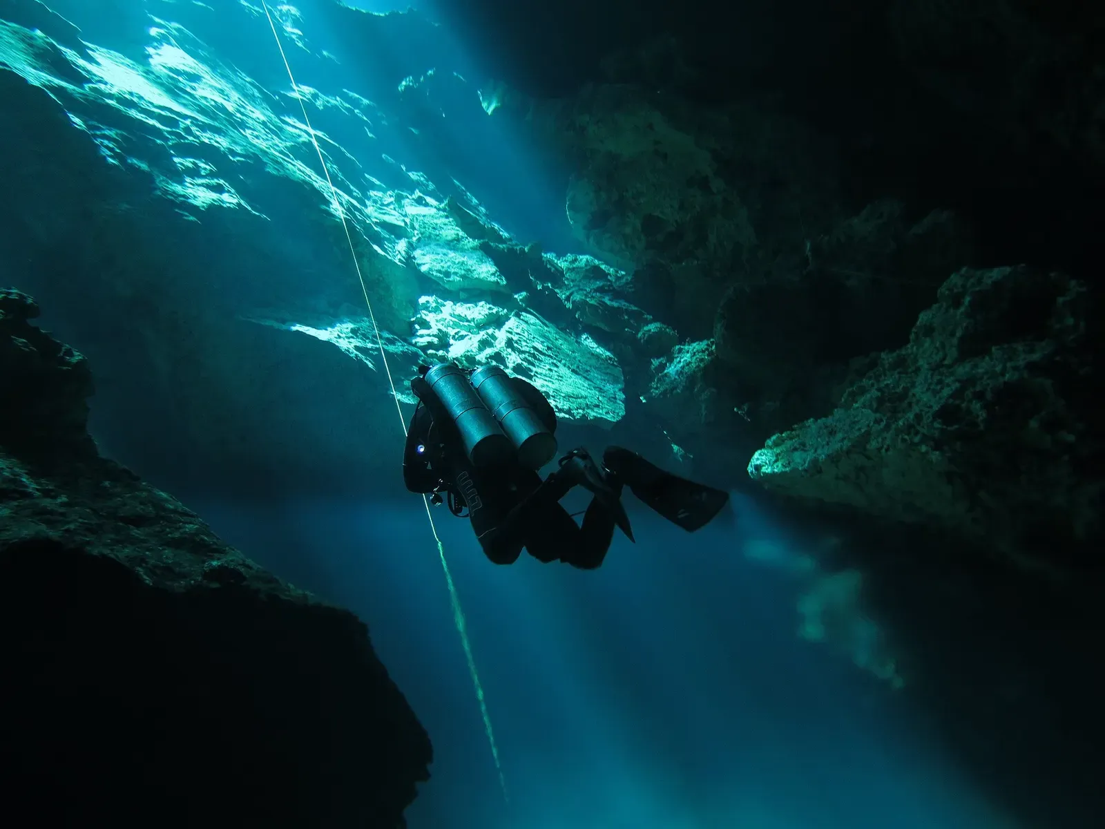 Diver descending past a rock overhang where the water blurs at the halocline