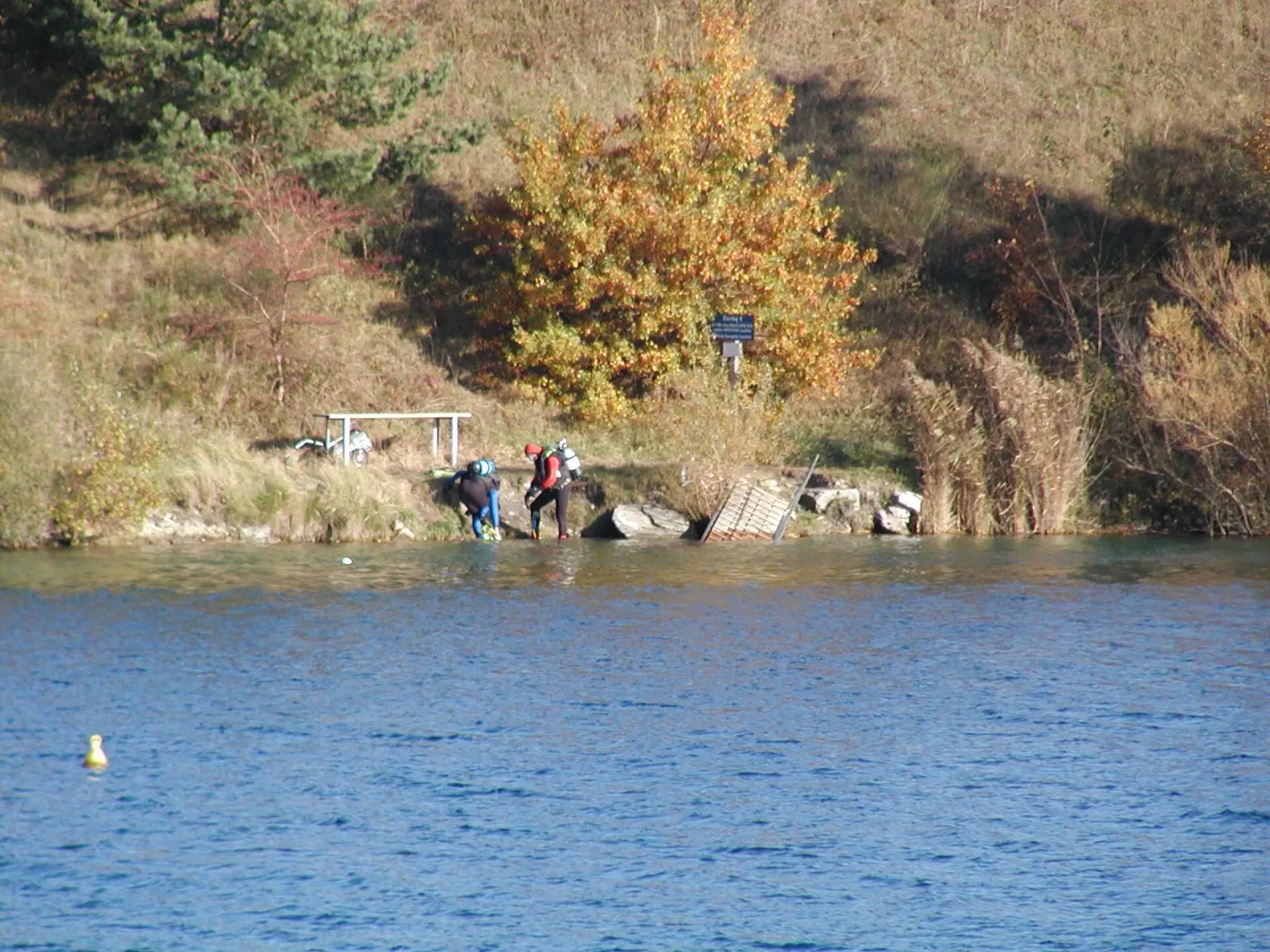 Divers kitting up at a wooden entry platform on the bank of the lake
