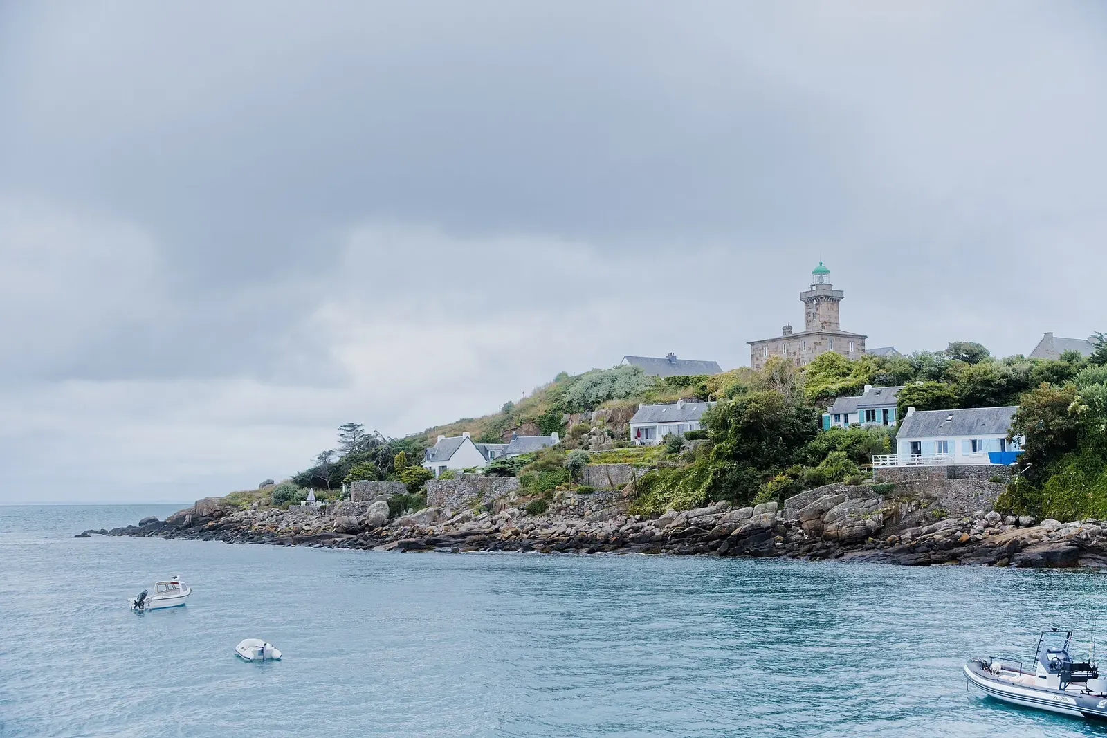 Chausey lighthouse above a rocky, wooded headland of Grande-Île, seen from the water — Chausey Islands & Granville