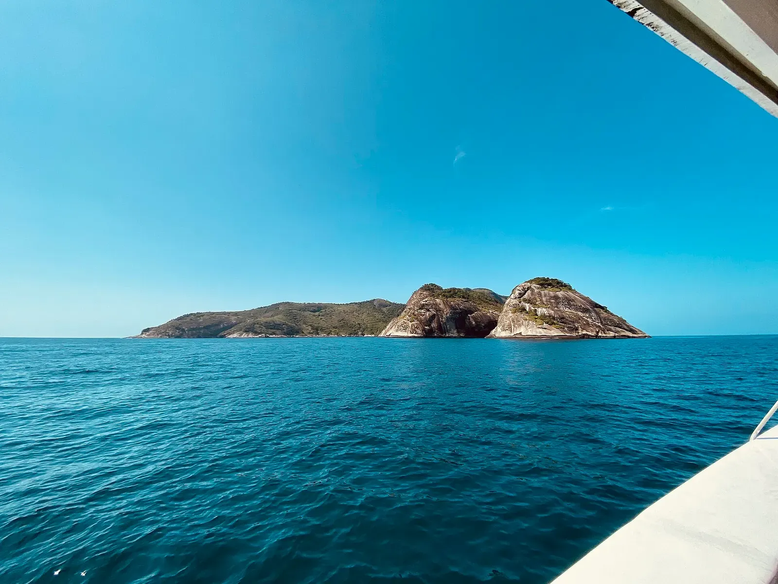 Distant view of Alcatrazes island with its twin rocky peaks across calm turquoise sea from a boat — Alcatrazes Archipelago