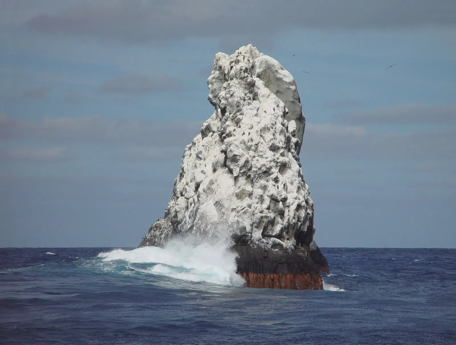 Waves break white against the sheer volcanic spire of Roca Partida — Socorro Island.