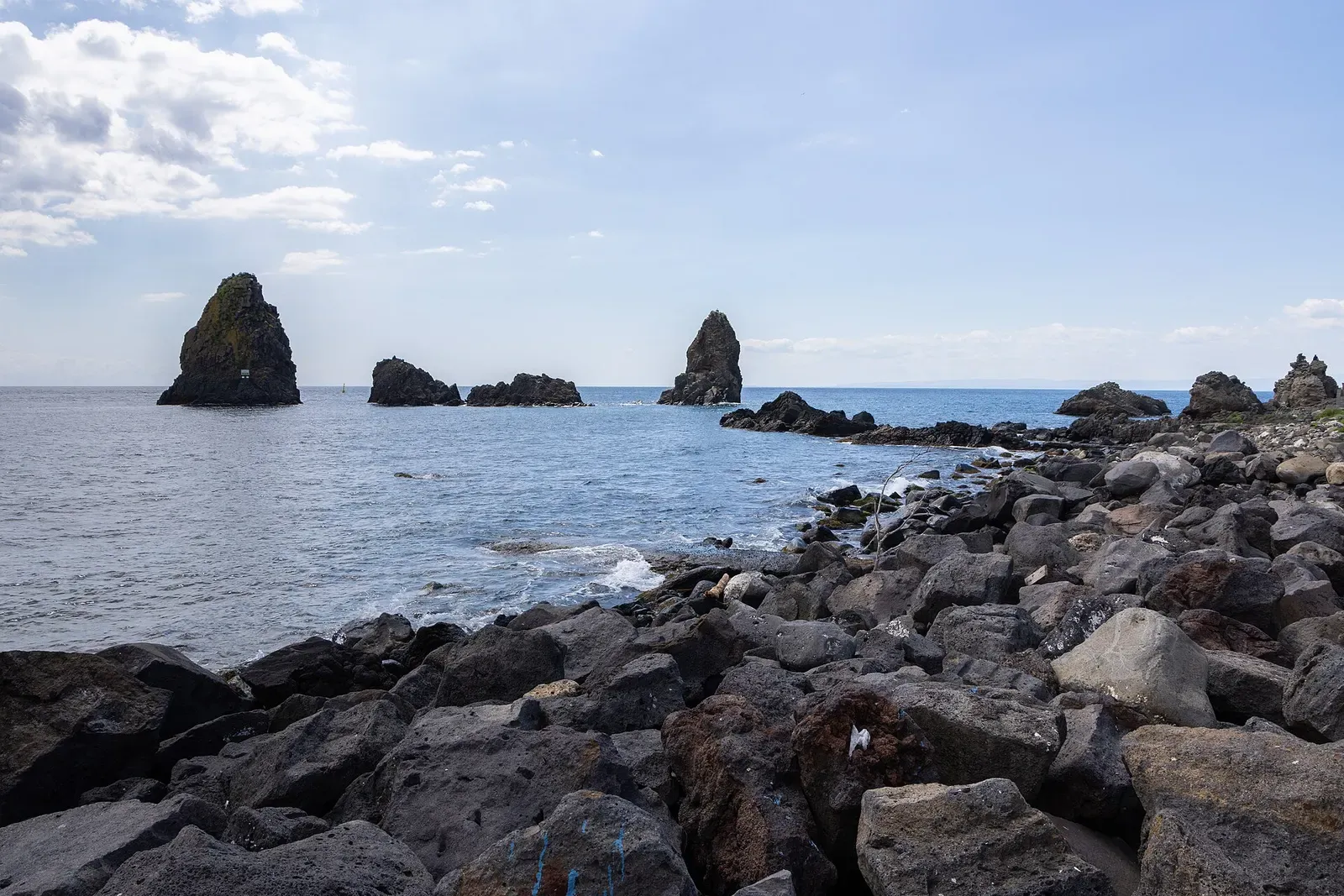 Several Cyclops sea stacks seen from the rocky shoreline at Aci Trezza