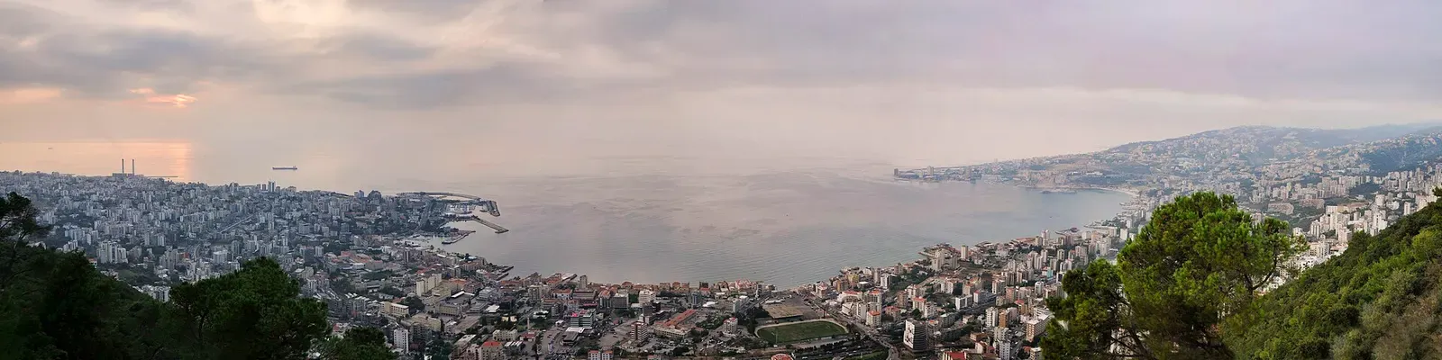 Panorama of Jounieh Bay under a hazy sky, the town and its stadium along the shore and open Mediterranean beyond