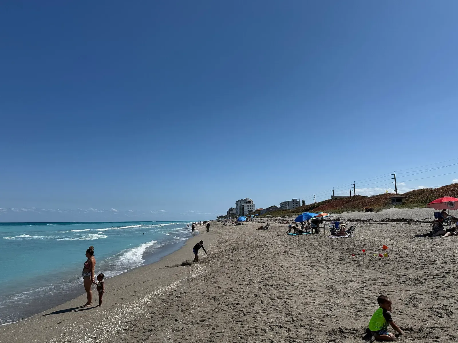 Sweeping coastal view of Juno Beach with gentle waves rolling onto pale Florida sand — Palm Beach & Jupiter