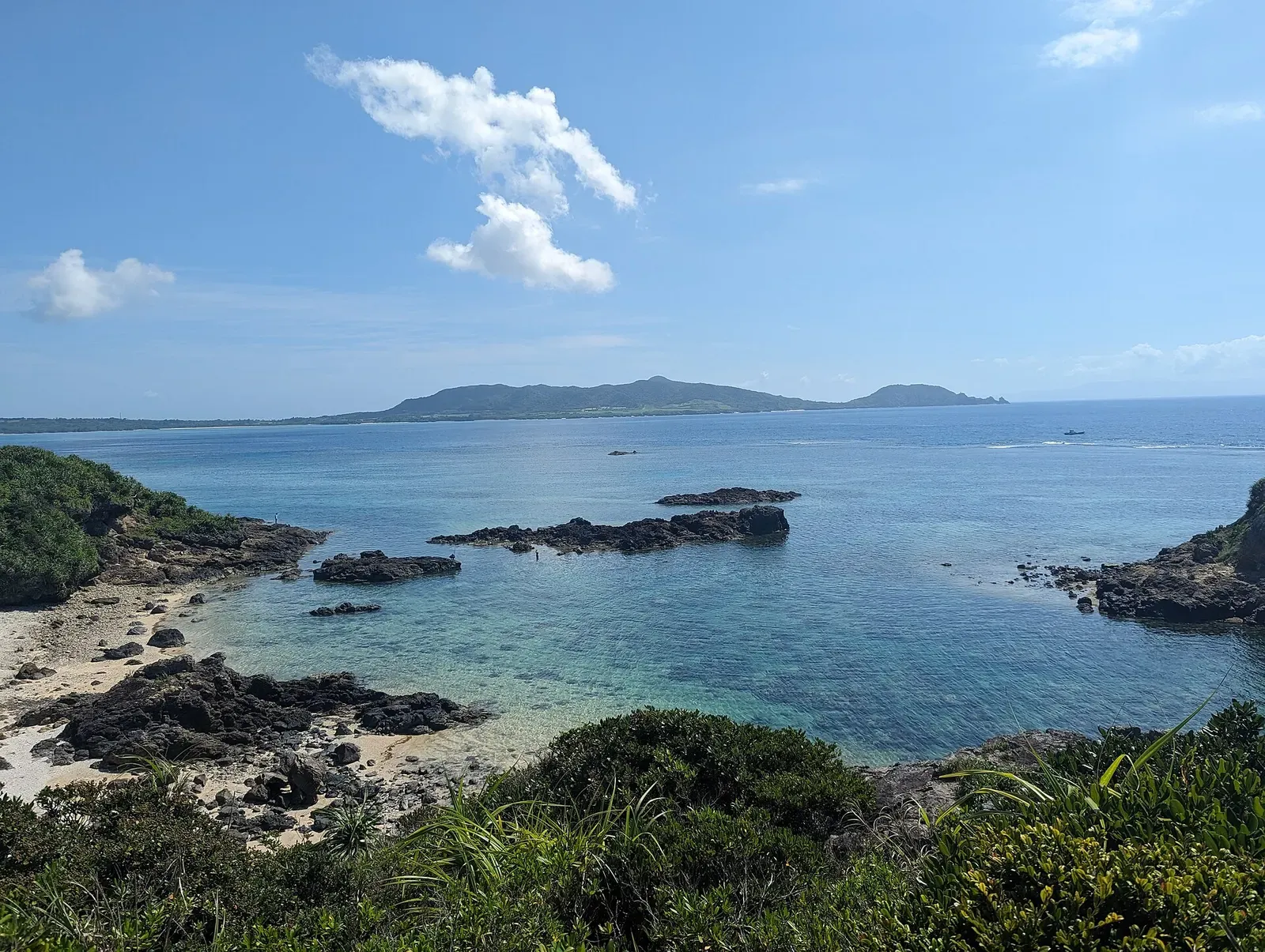 Wide view of the reef flat and offshore islands from a coastal overlook near the point — Manta City, Ishigaki