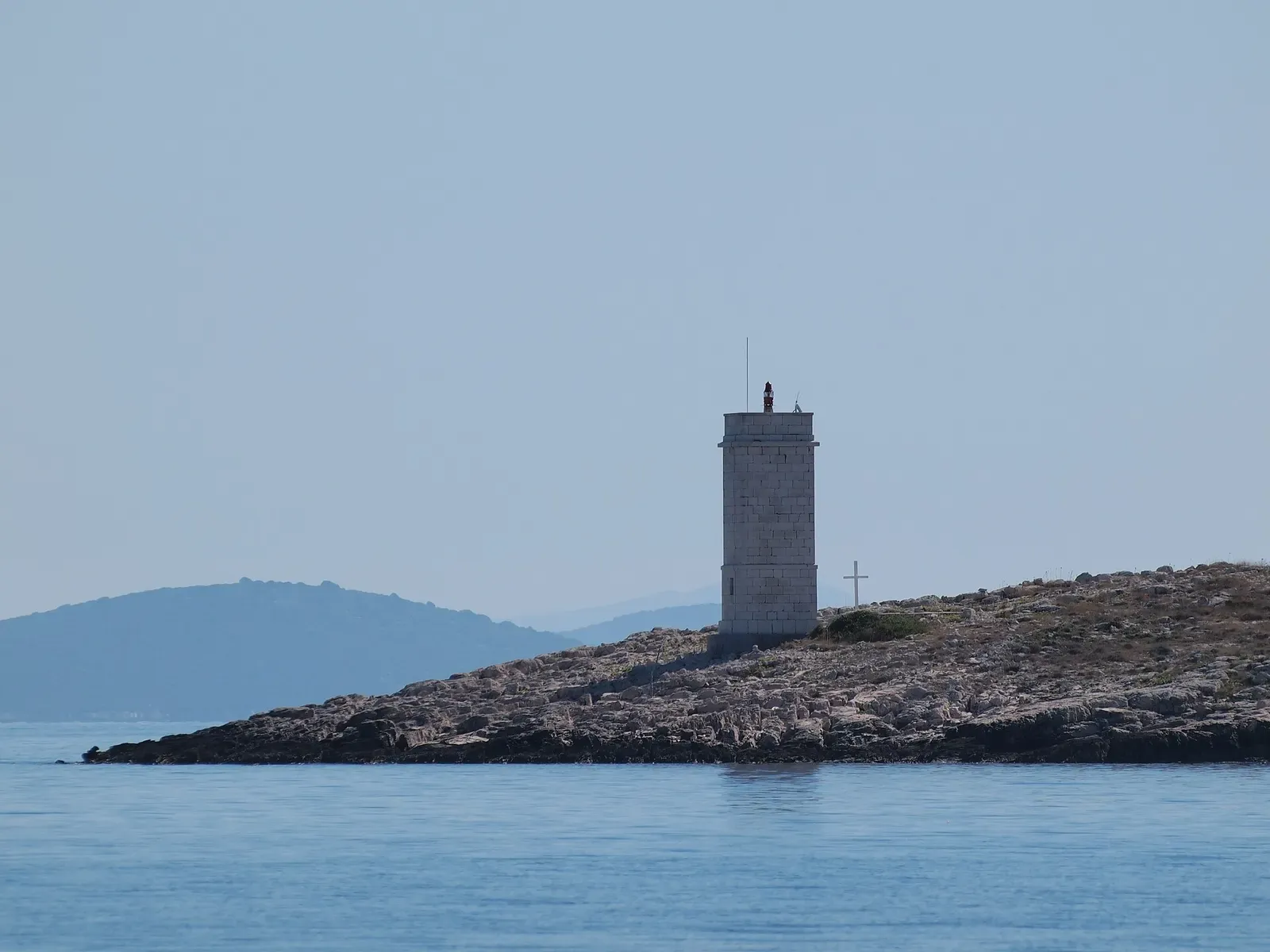 The lighthouse on Smokvica Vela, seen across the water from offshore — Smokvica Vela Wall, Kornati Islands.