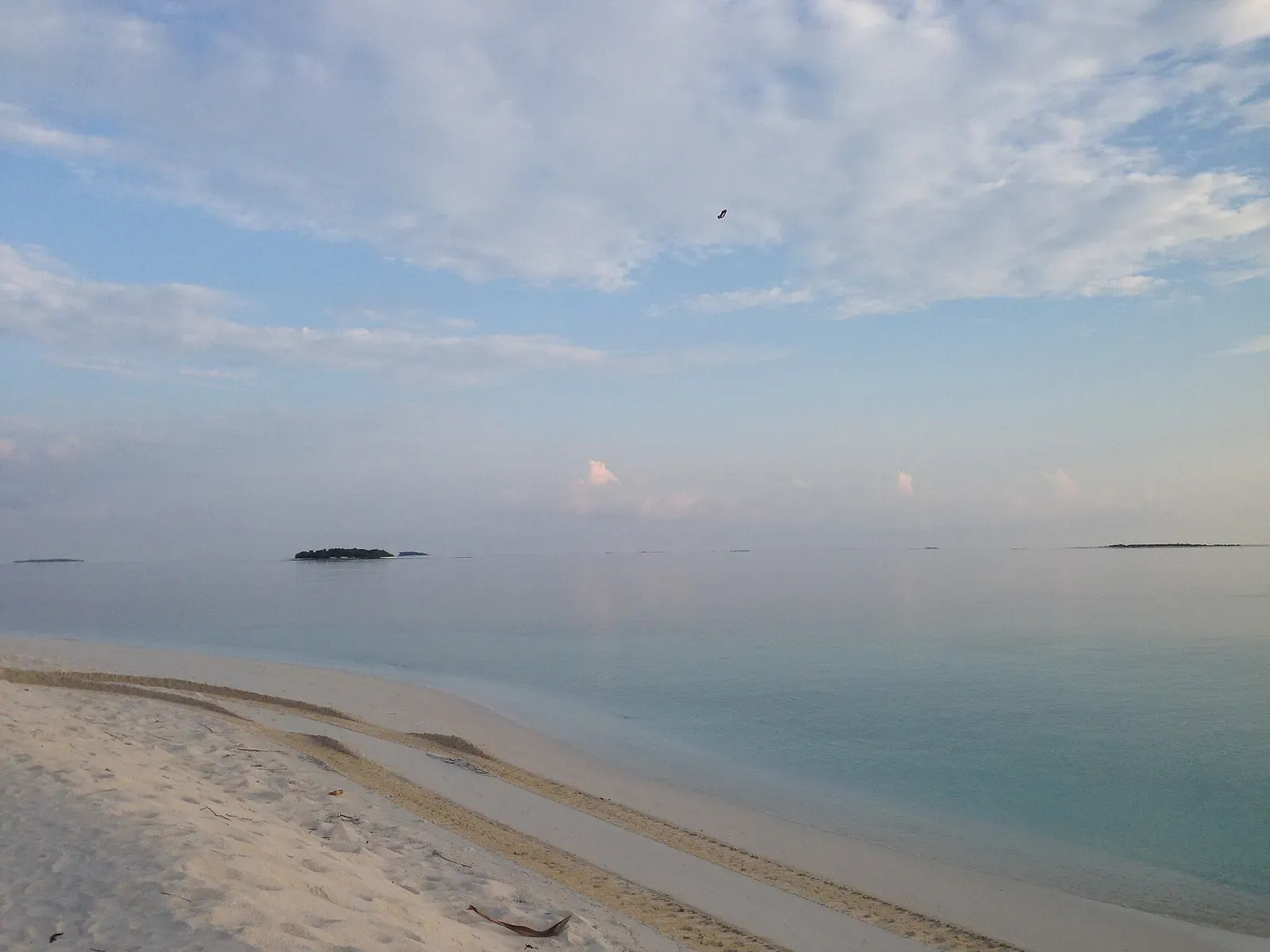 White sand spit stretching into the lagoon with a small island visible on the horizon in Raa Atoll