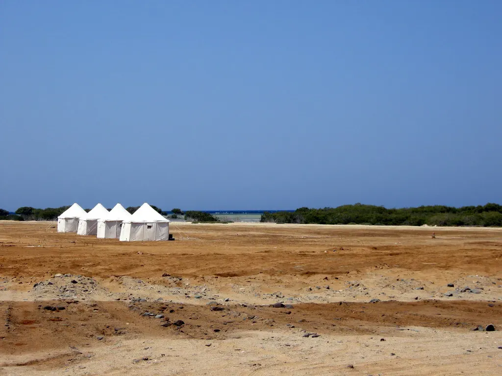 White A-frame tents of a desert dive camp near the shoreline at Wadi Lahami.