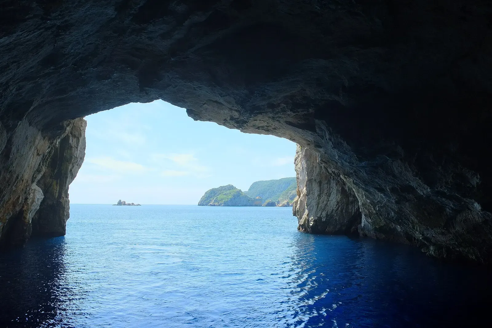 A second view out through the mouth of Rikoriko Cave toward open water and distant cliffs — Poor Knights Islands.