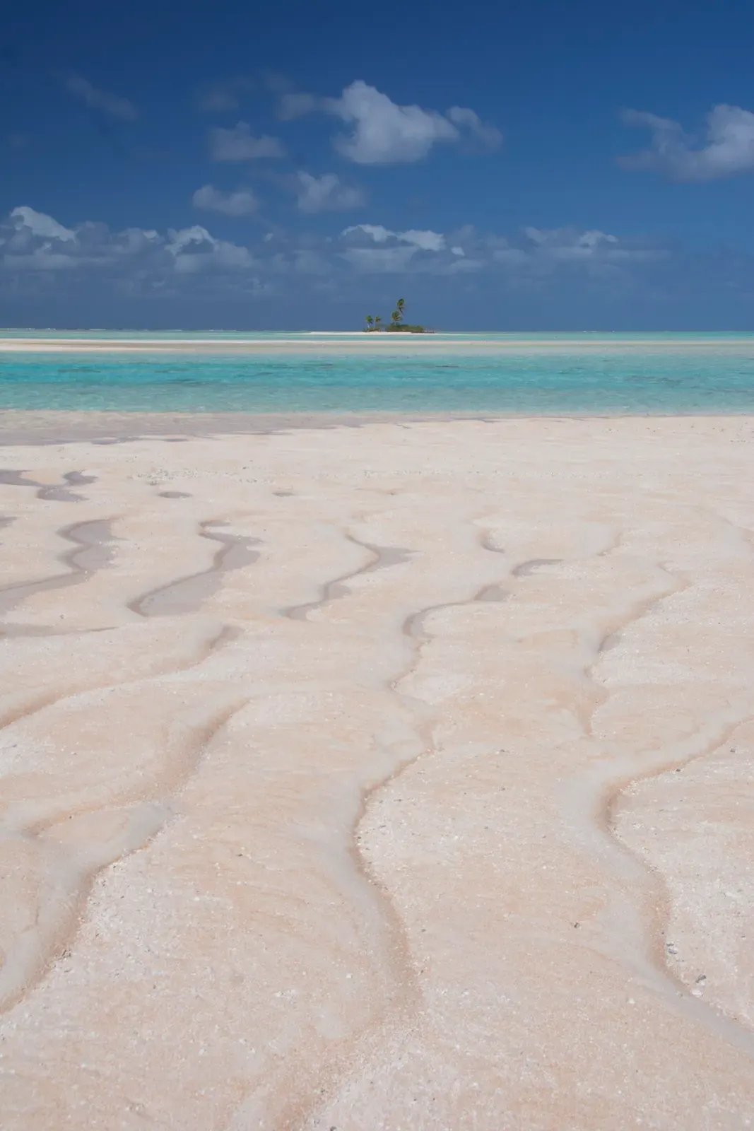 Rippled pink sand flat facing a small palm motu near Fakarava South Pass