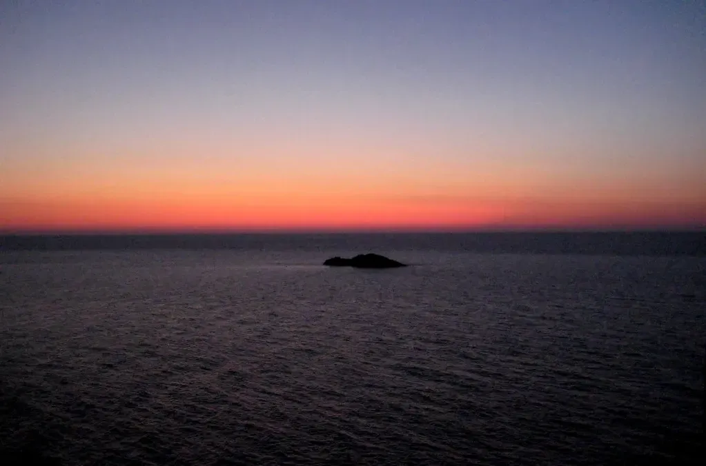 Silhouette of the isolated Scoglio del Medico rock at sunset, seen from open water — Ustica