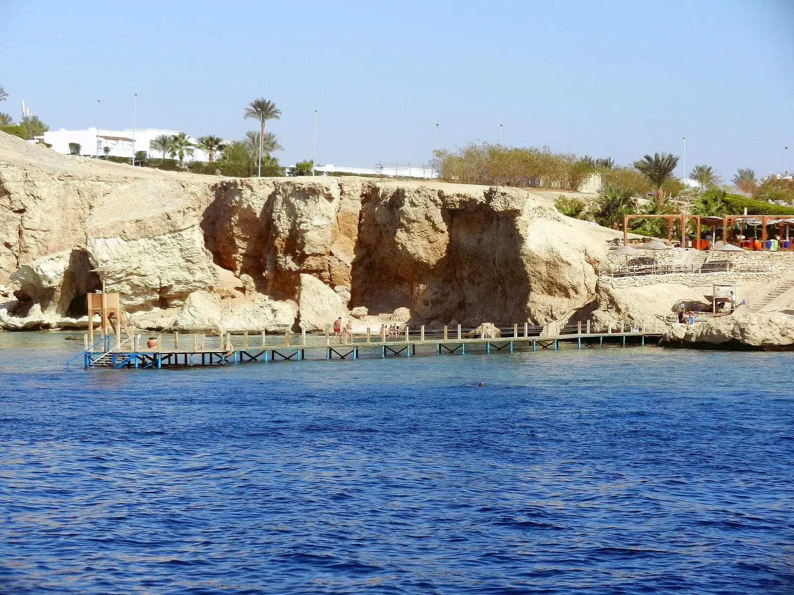 Rocky headland and wooden jetty at the Ras Umm Sid shore entry point — Sharm El Sheikh.