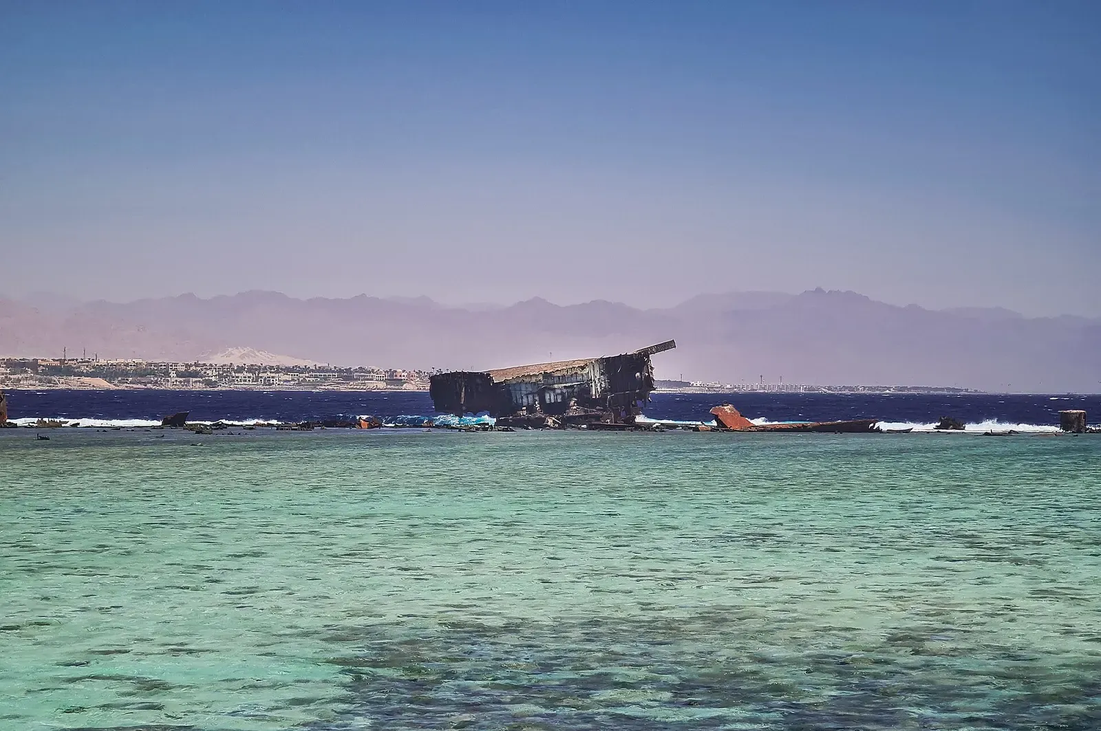 Low rusted wreck at Jackson Reef silhouetted against the Sinai mountains at dusk — Sharm El Sheikh.