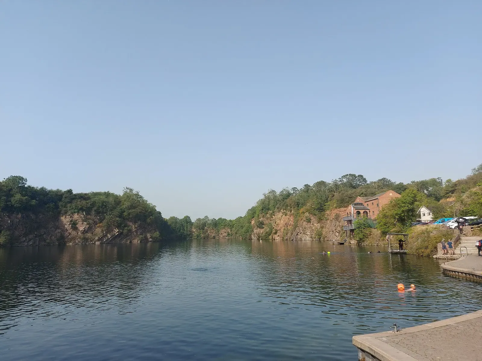 Wide view across the still water of the quarry to its wooded far wall