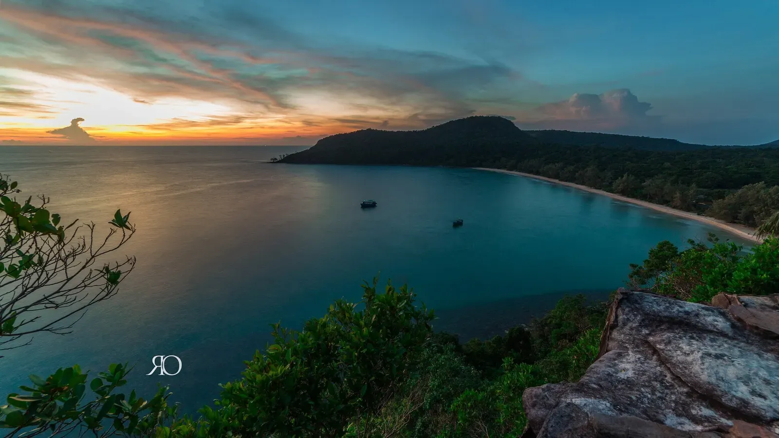 Colorful sunset over the sheltered lagoon at Lazy Beach, Koh Rong Samloem, with boats at anchor.