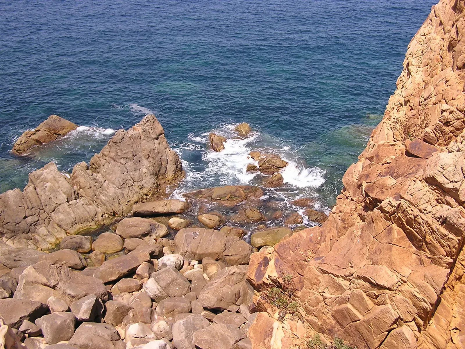 Clear turquoise water surging over ochre rocks below a coastal massif — Tabarka