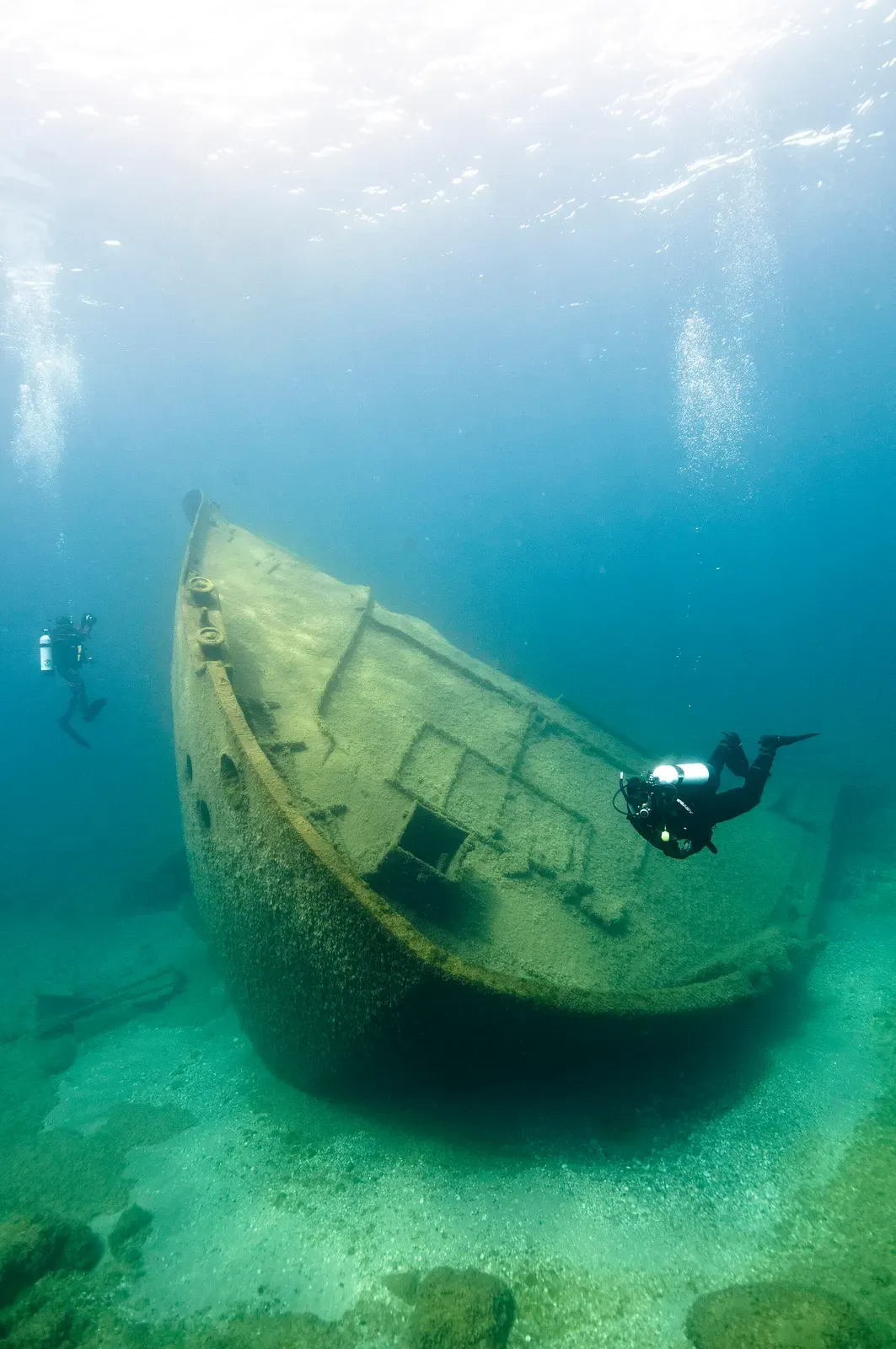 Diver approaches the submerged hull of the Nordmeer freighter in green Lake Huron water — Thunder Bay