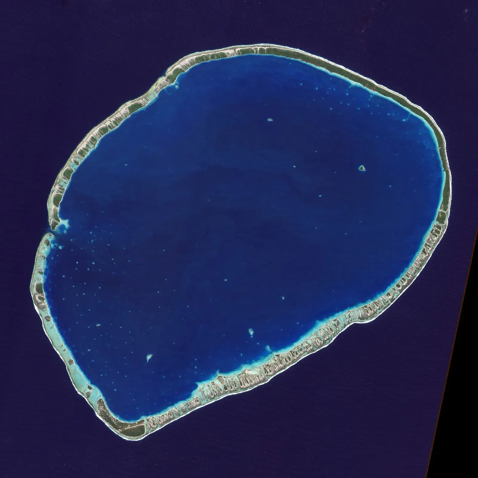 Satellite image of a near-circular atoll with a continuous reef rim enclosing a deep blue lagoon — Tikehau
