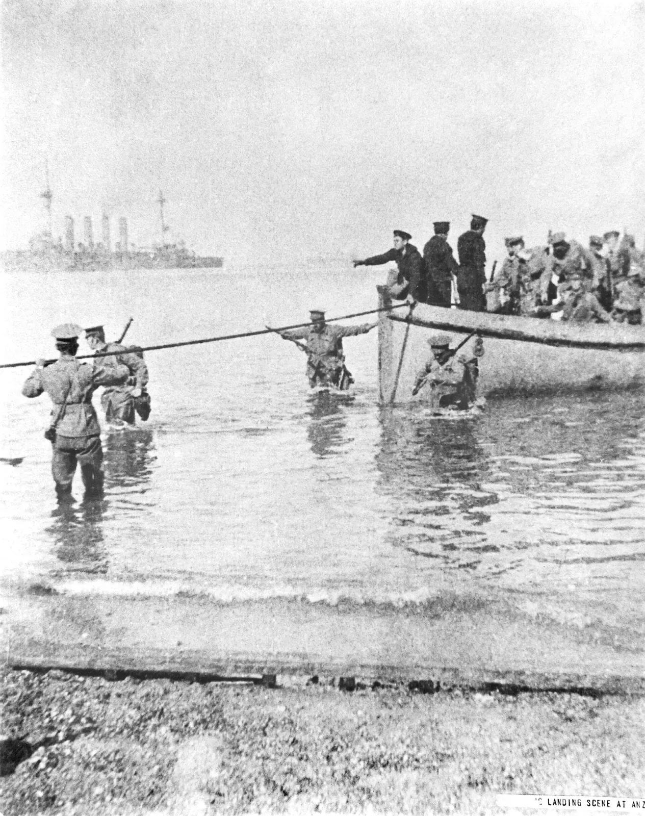 A 1915 photograph of soldiers wading ashore from a boat at Anzac Beach while a warship lies offshore — Gallipoli.