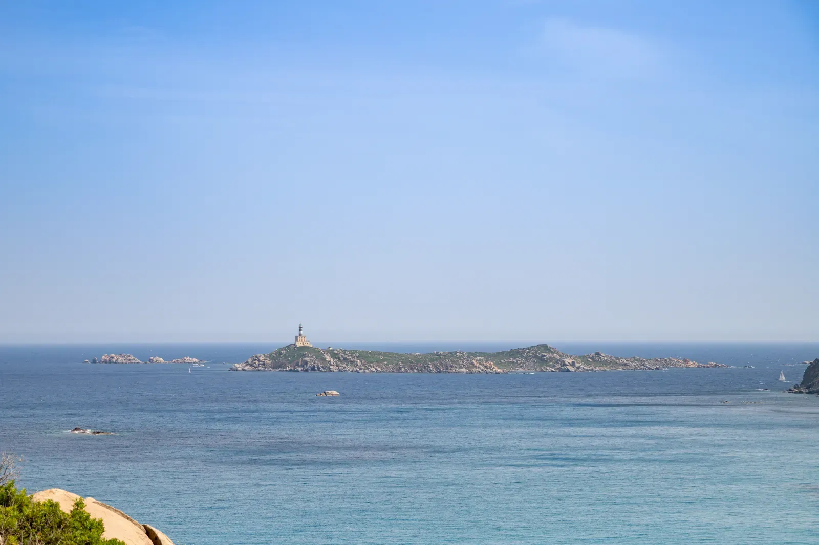 Isola dei Cavoli and its lighthouse seen across calm blue water from the Sardinian shore — Capo Carbonara