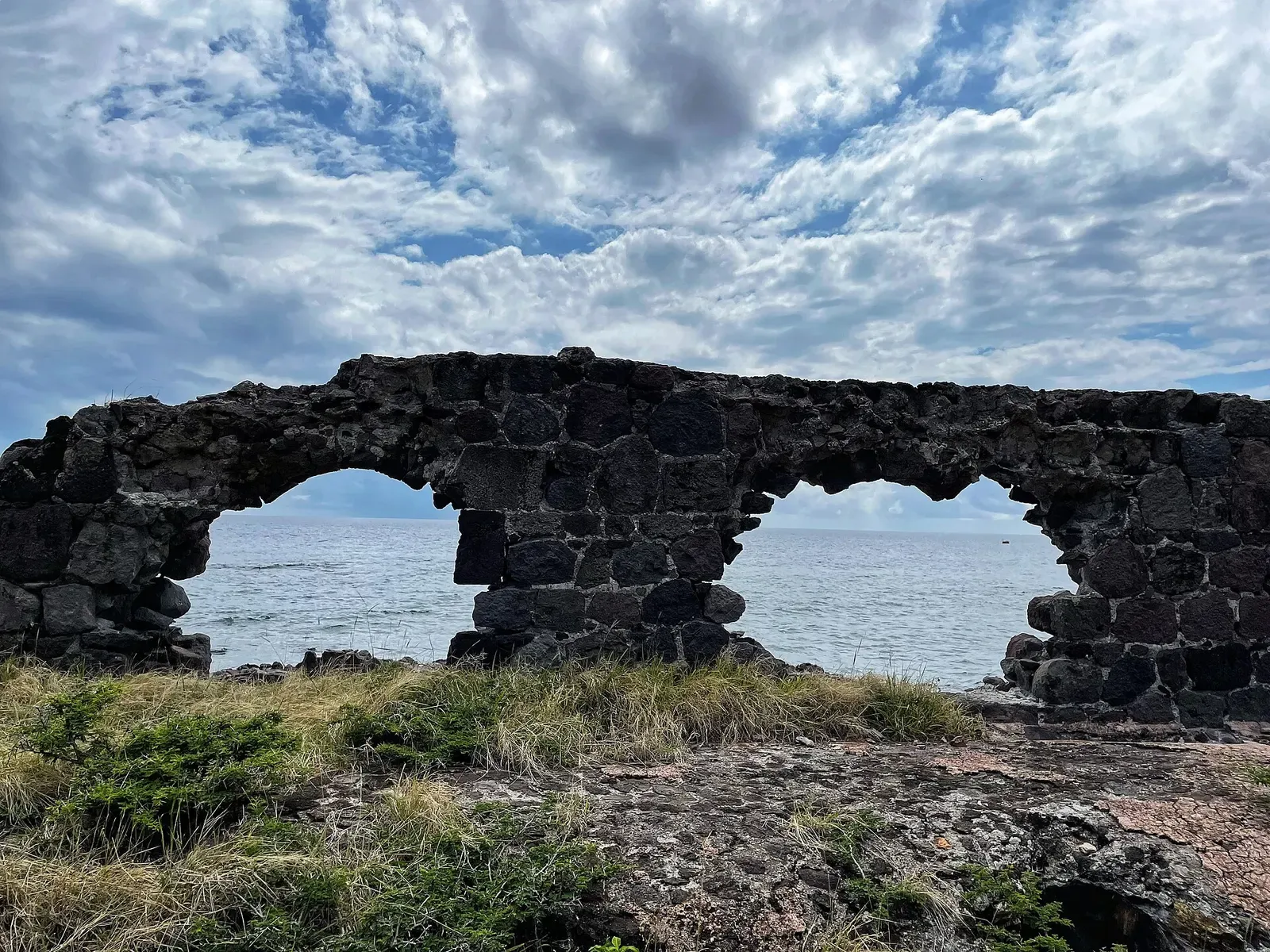Rusted pilings of a colonial-era warehouse standing in clear shallow water at the Lower Town waterfront — St. Eustatius