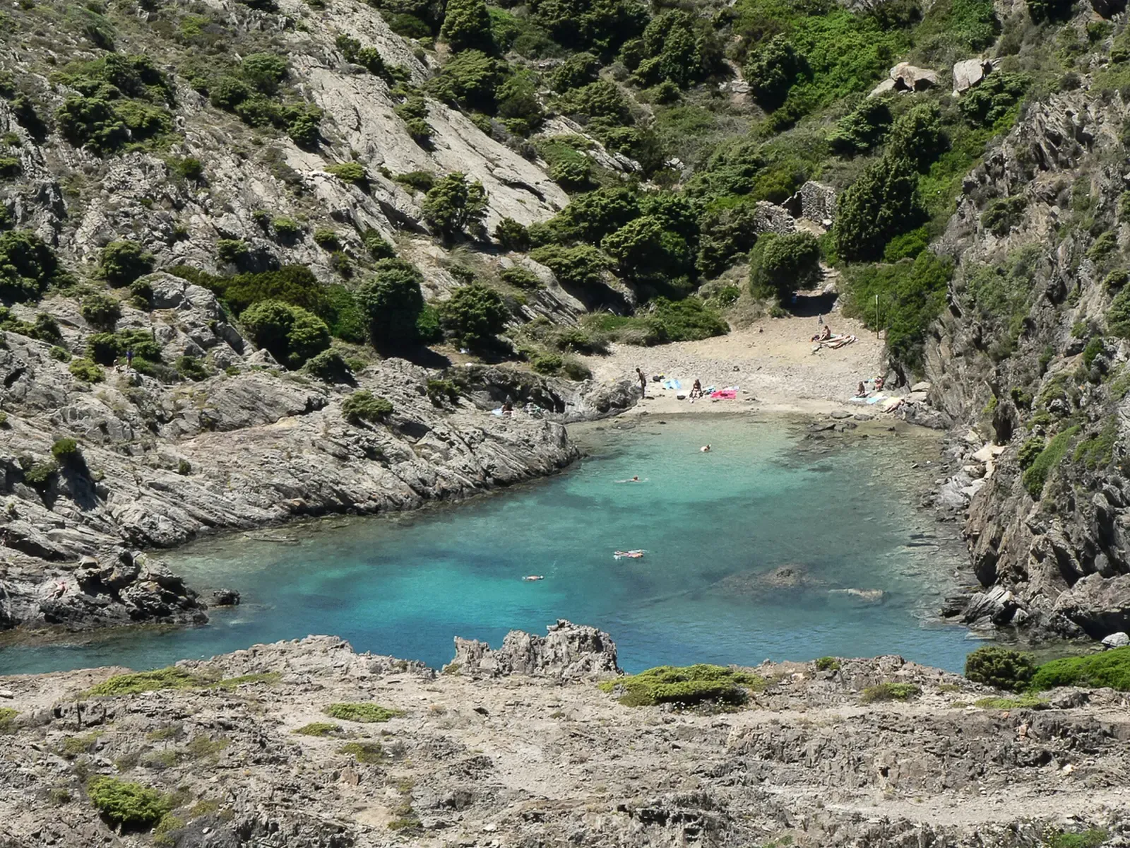 Close view of the turquoise cove at Cala Jugadora, with swimmers near the rocky shoreline — Cap de Creus