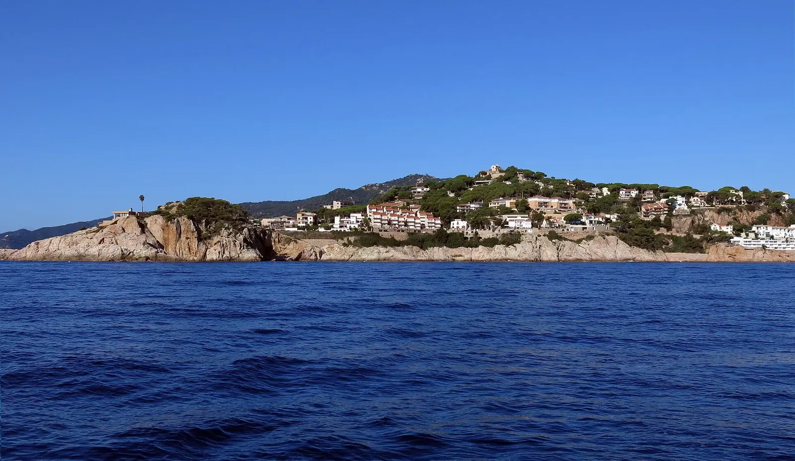 Headland of Sant Elm and Punta de Garbí with hillside houses, seen from the sea