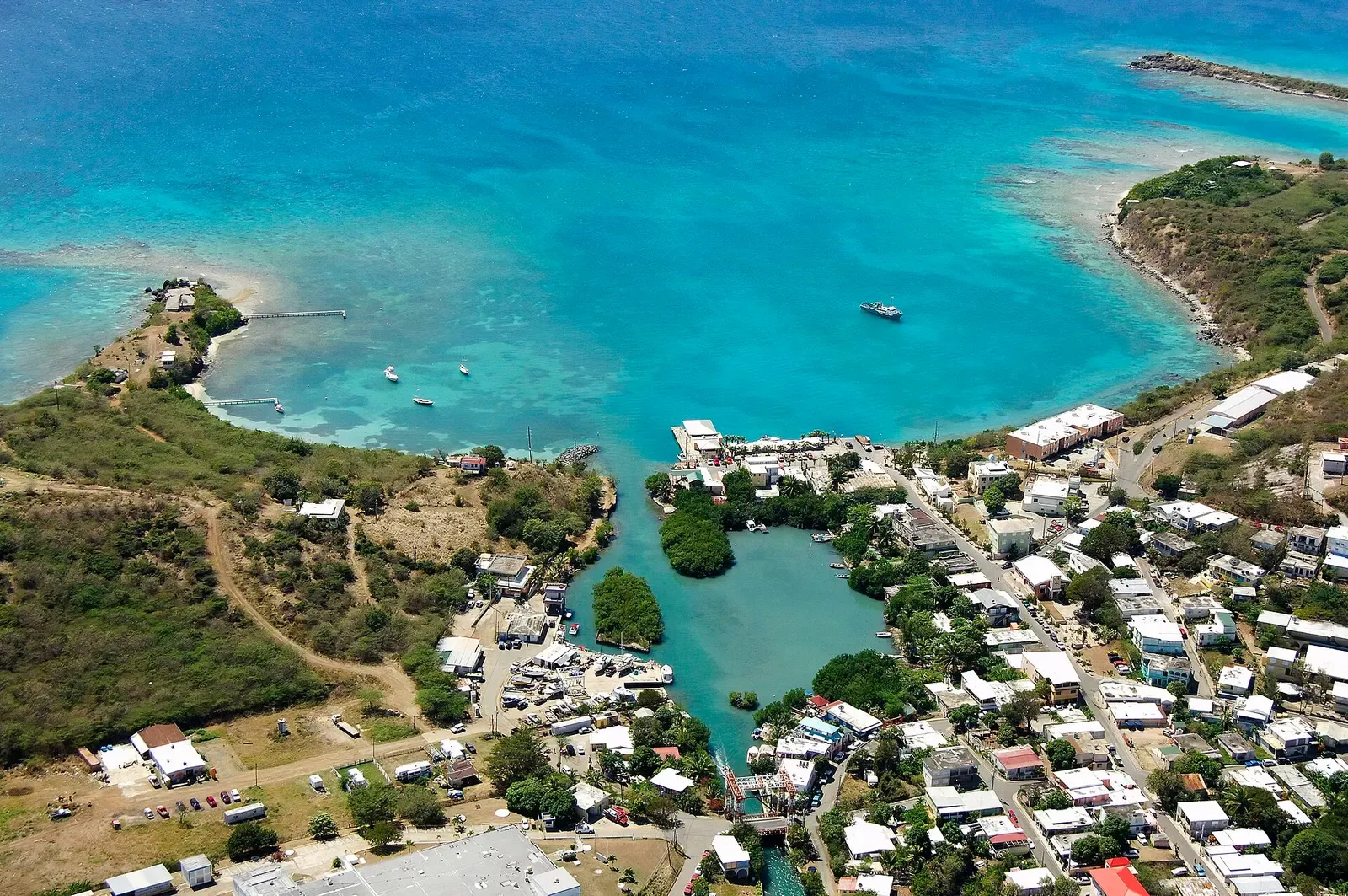 Aerial view of Dewey village, its lagoon channel and the ferry landing, with reef-patched turquoise water beyond — Culebra.