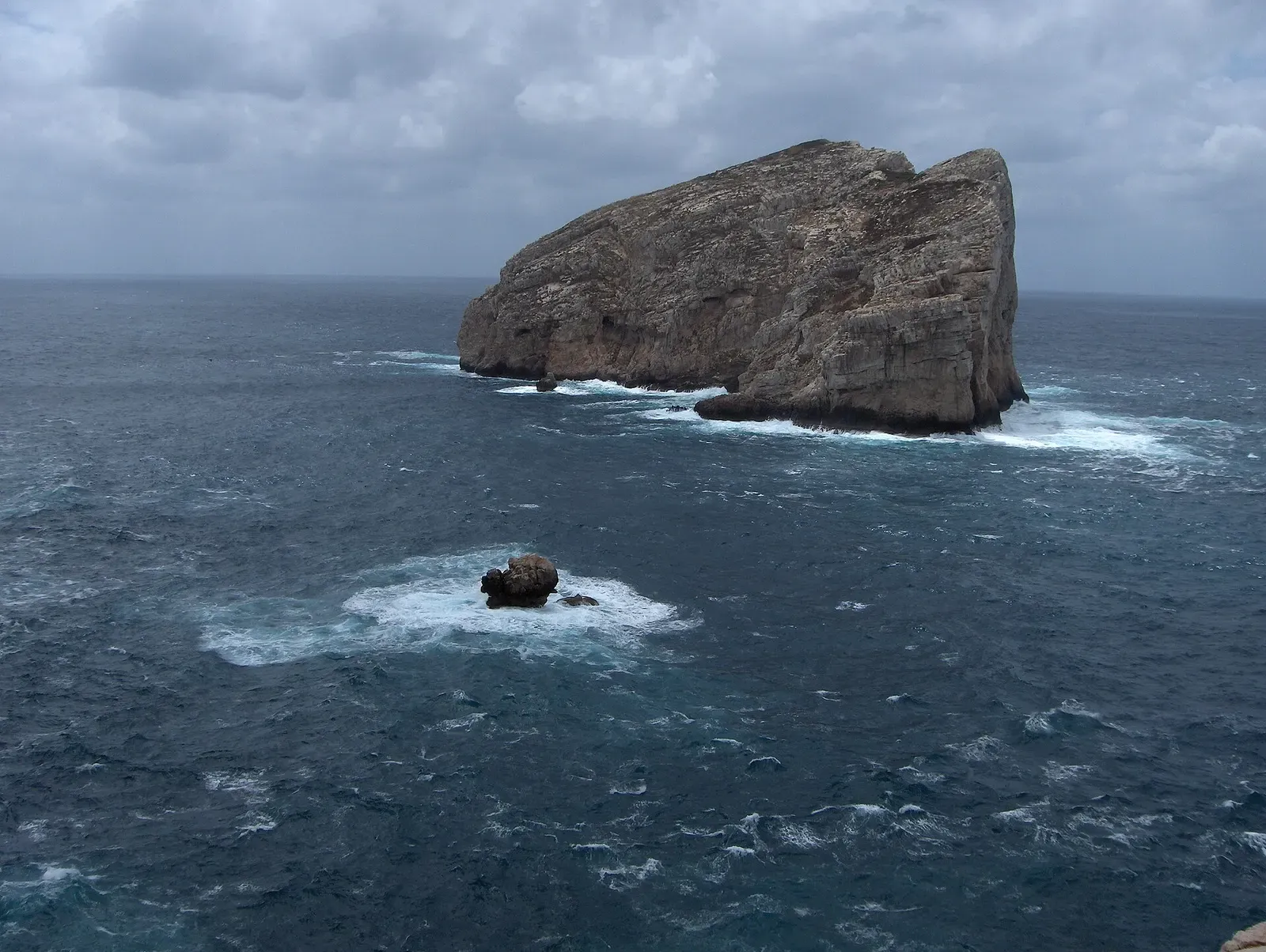 Isola Foradada under an overcast sky, viewed from the Capo Caccia headland