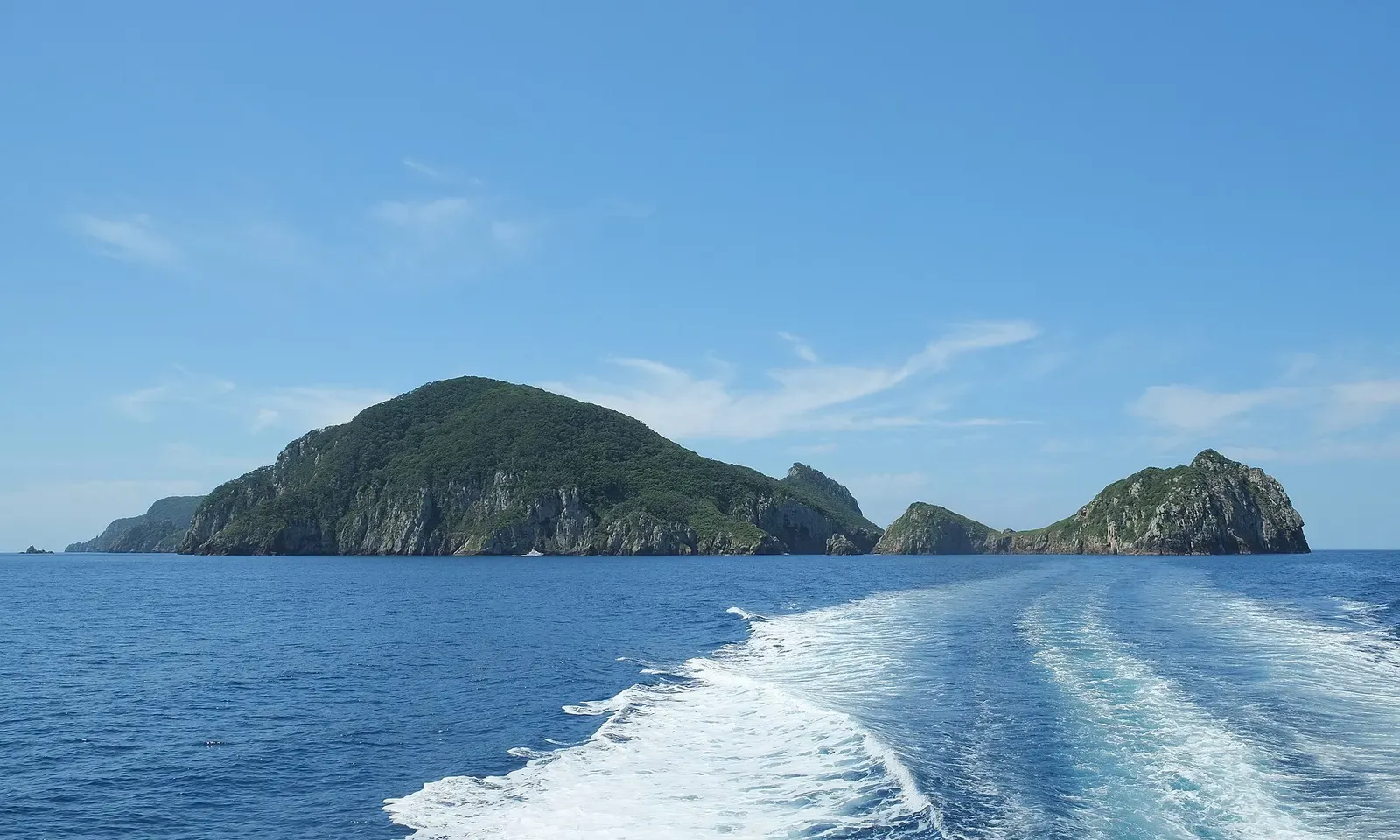 Aorangi Island and the smaller Archway Island together, seen from the water south of the main island — Blue Maomao Arch, Poor Knights Islands.