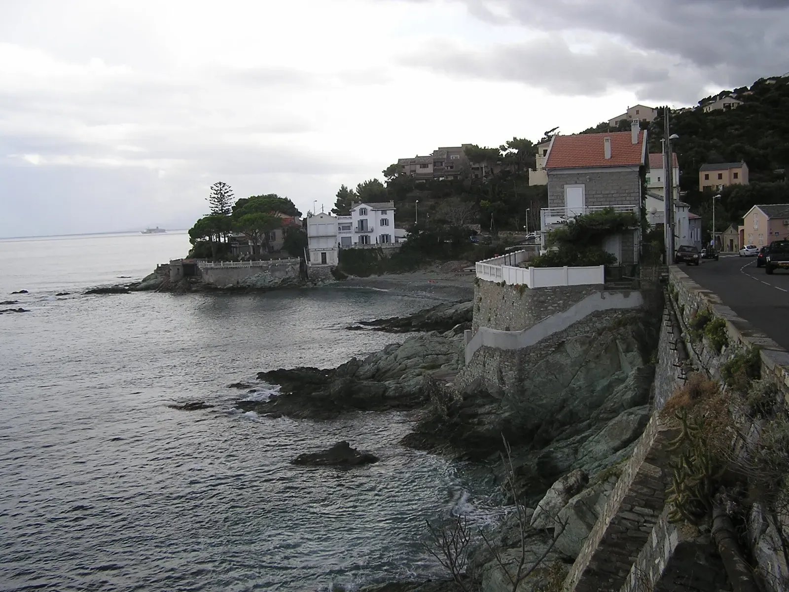 Rocky headland with a stone tower and white houses above the sea near Bastia